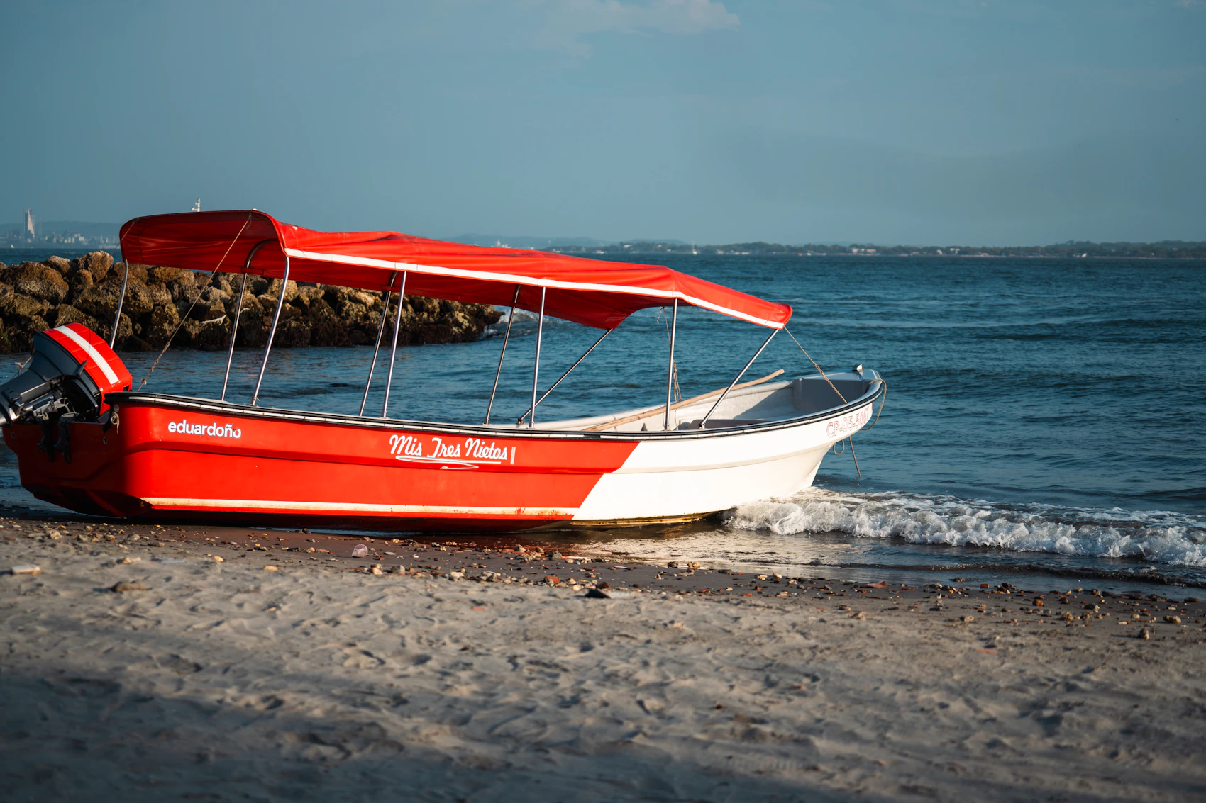 A red and white local boat resting at the edge of a Cartagena beach
