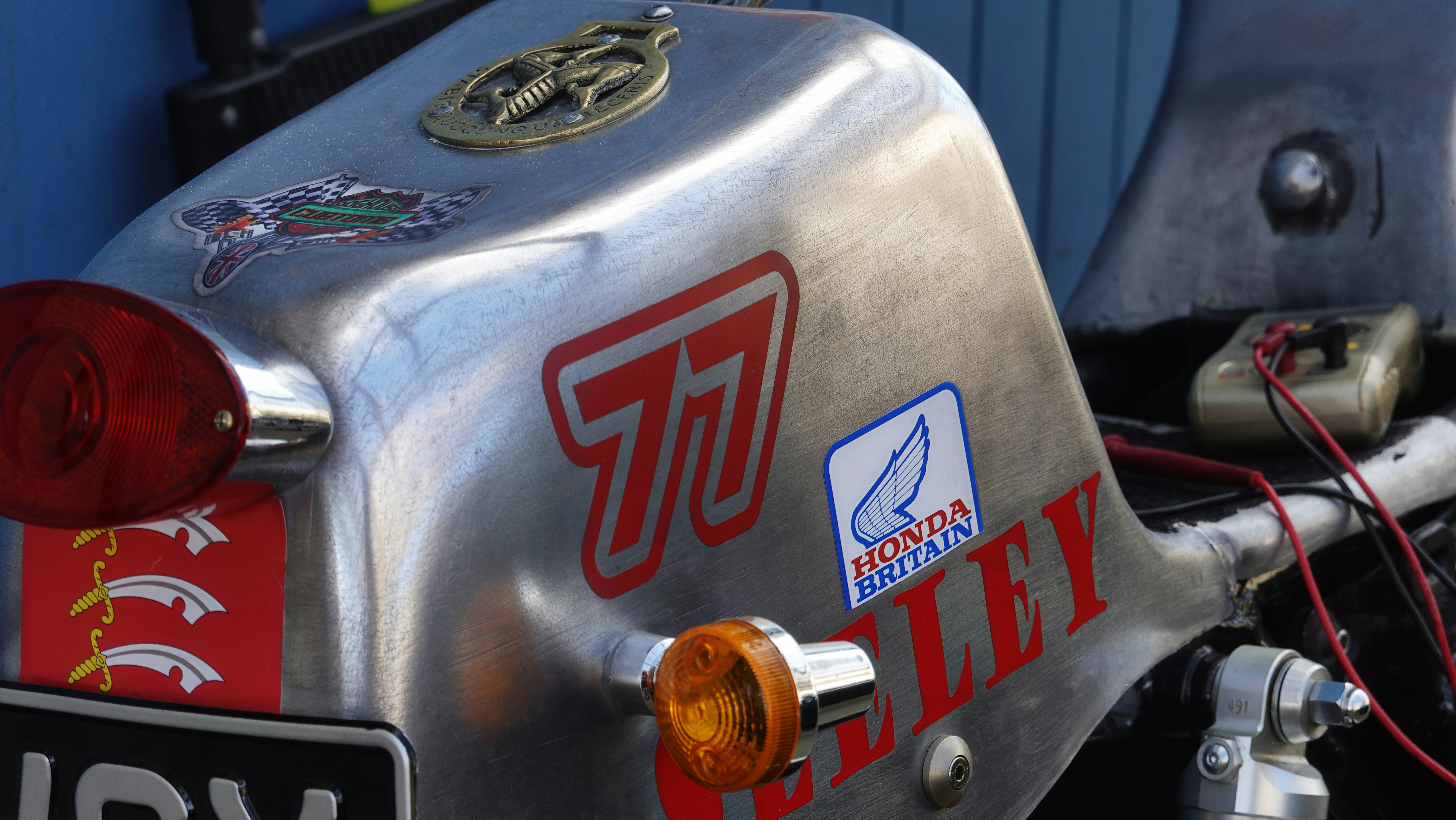 Close-up of a vintage motorcycle fuel tank with stickers.