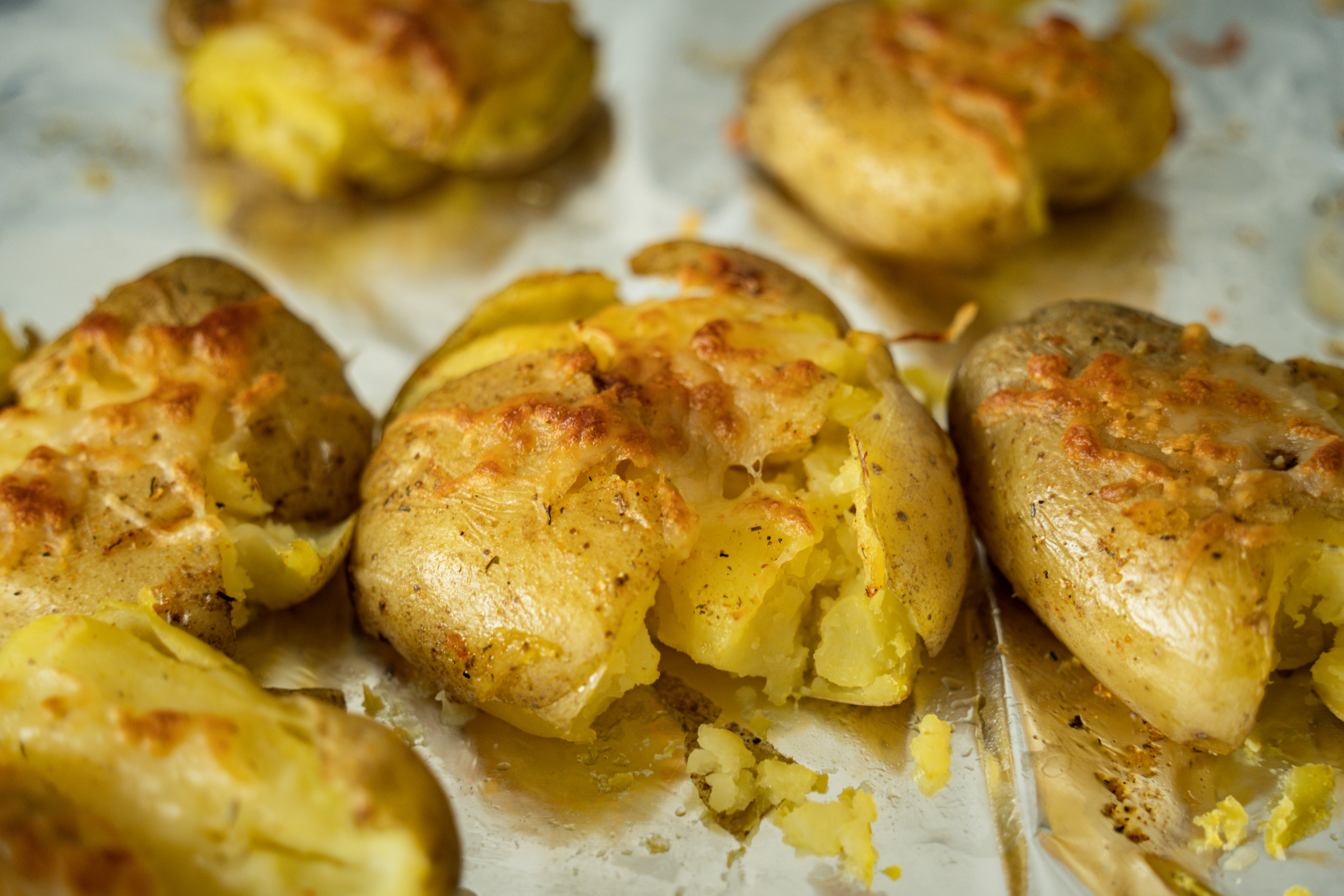 Several smashed potatoes with spices on a tray