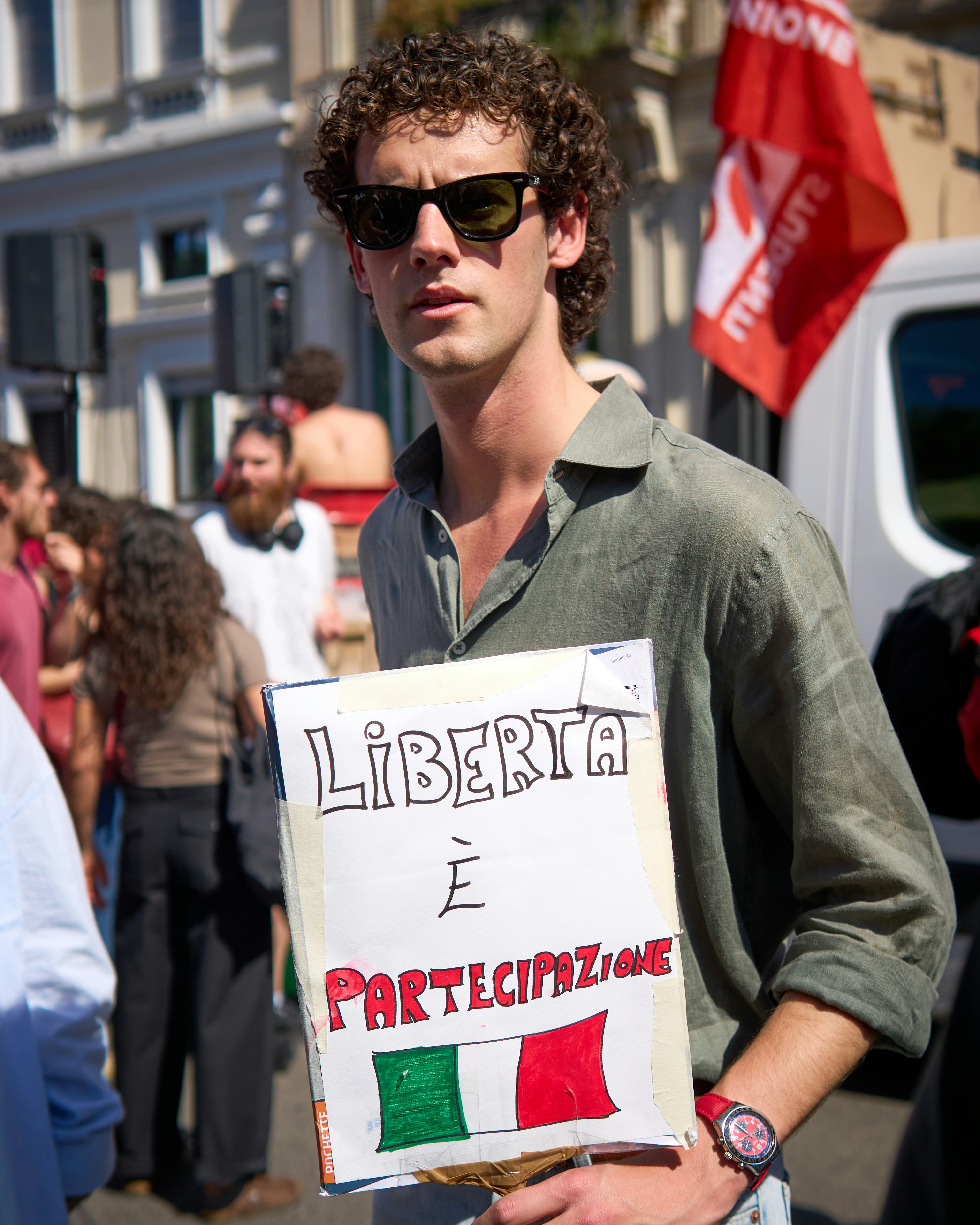 Young man holds sign with italian flag and text.