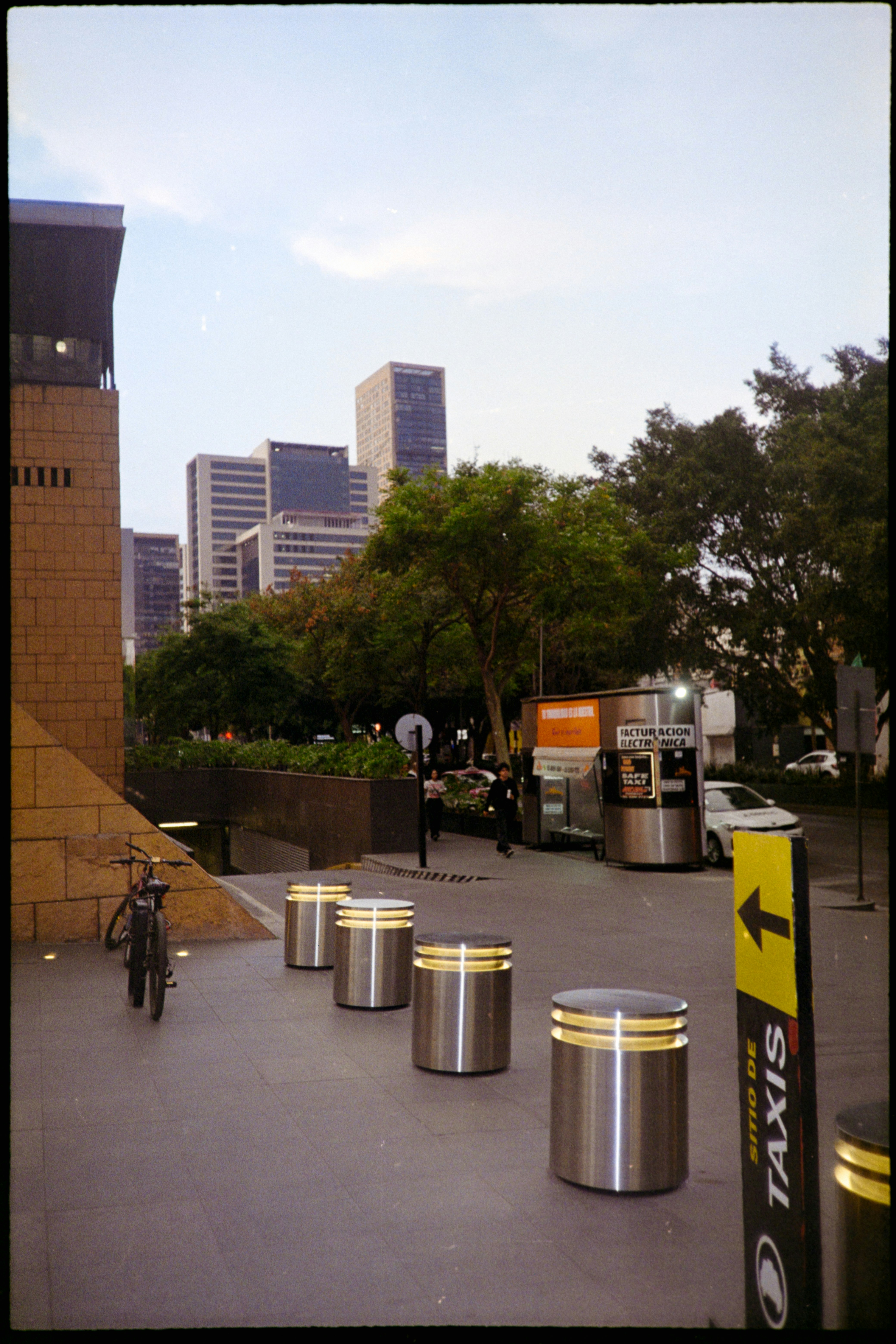 City street with buildings, trees, and taxi stand.
