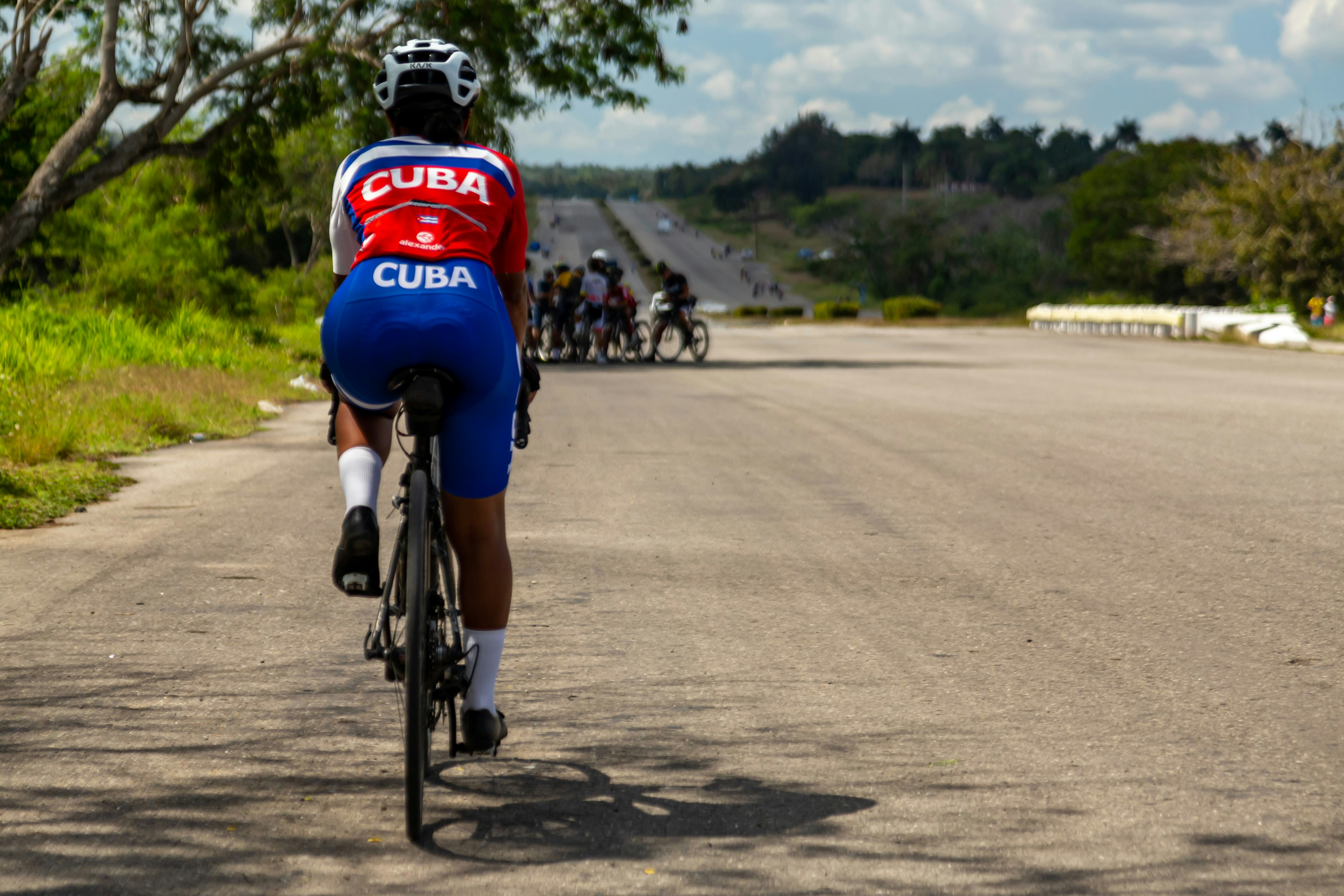 I ciclisti a Cuba corrono lungo una strada lunga e rettilinea.