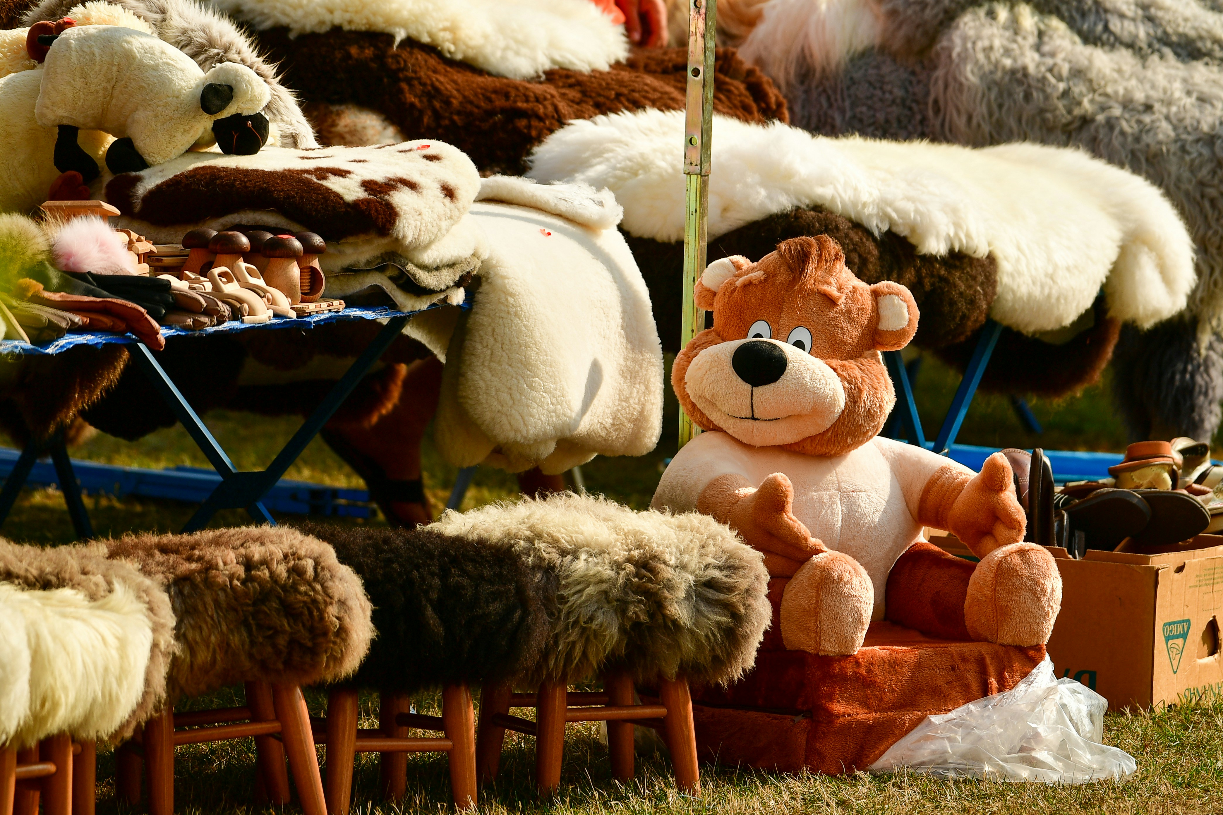 A handicraft market stall during the Saaremaa Maritime Days in Kuressaare, showcasing traditional handmade items including sheepskin rugs, wooden crafts, and a charming plush bear on display
