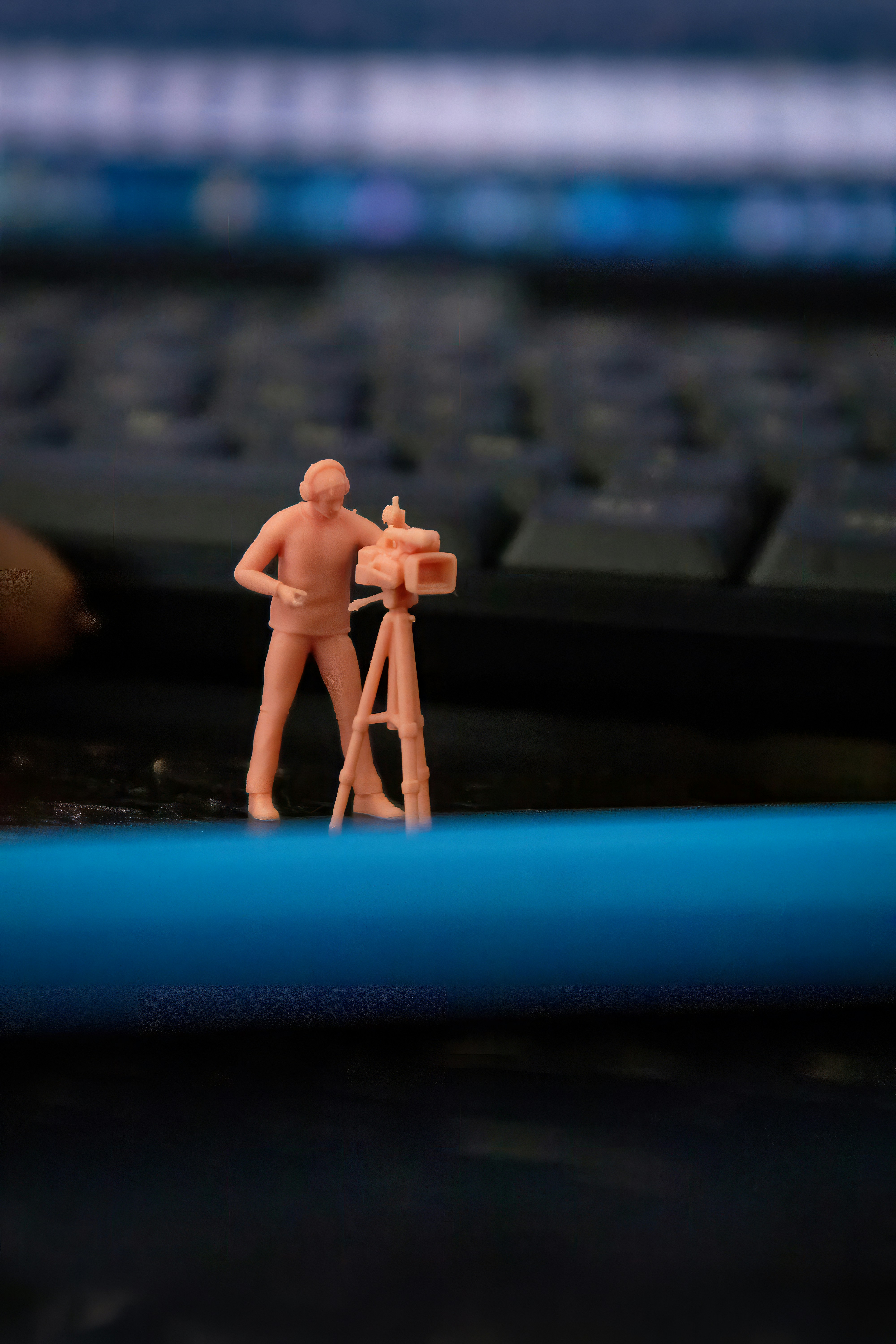 Miniaturfigur, die eine Videokamera auf einem Stativ bedient.