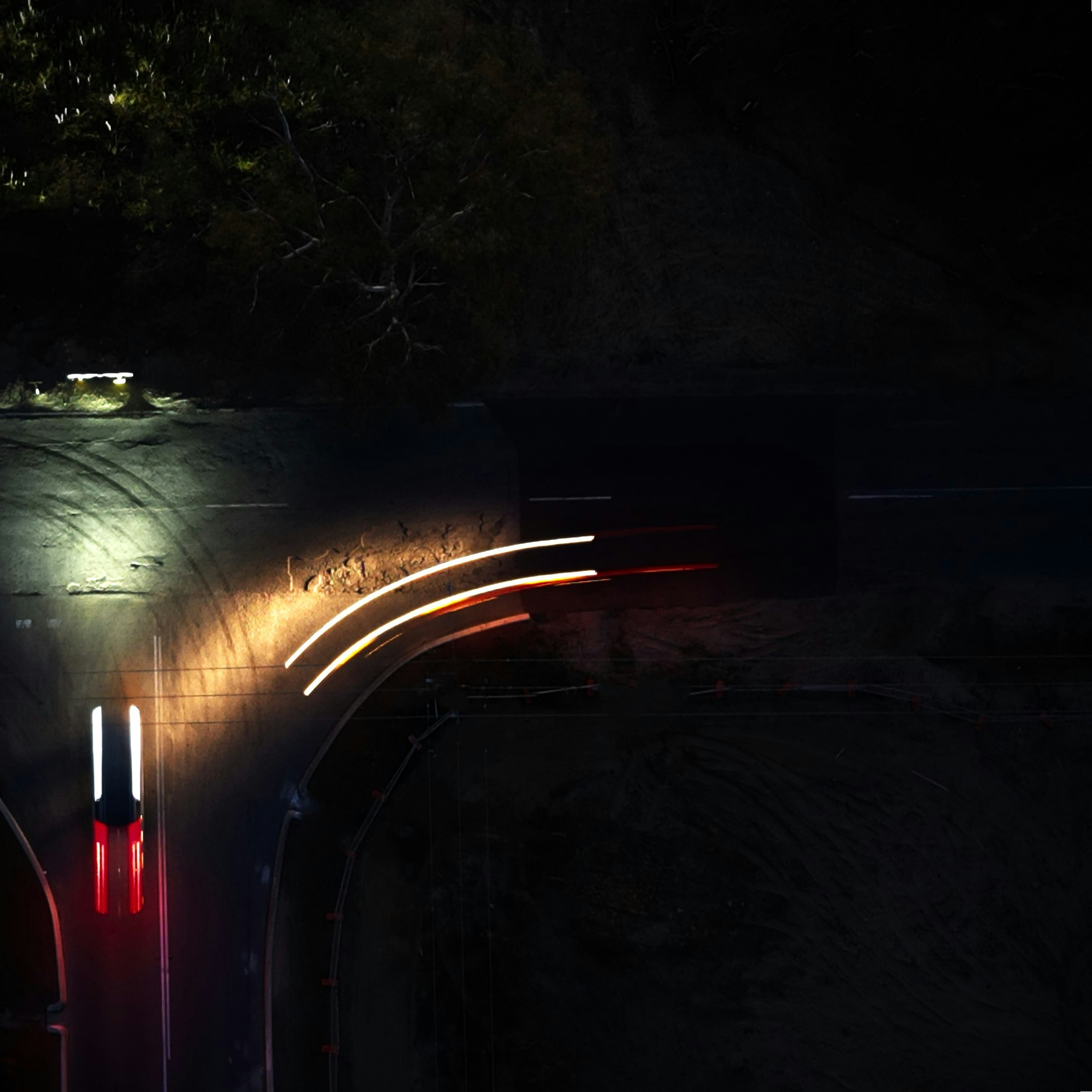 Faróis de carros iluminam uma estrada escura à noite.
