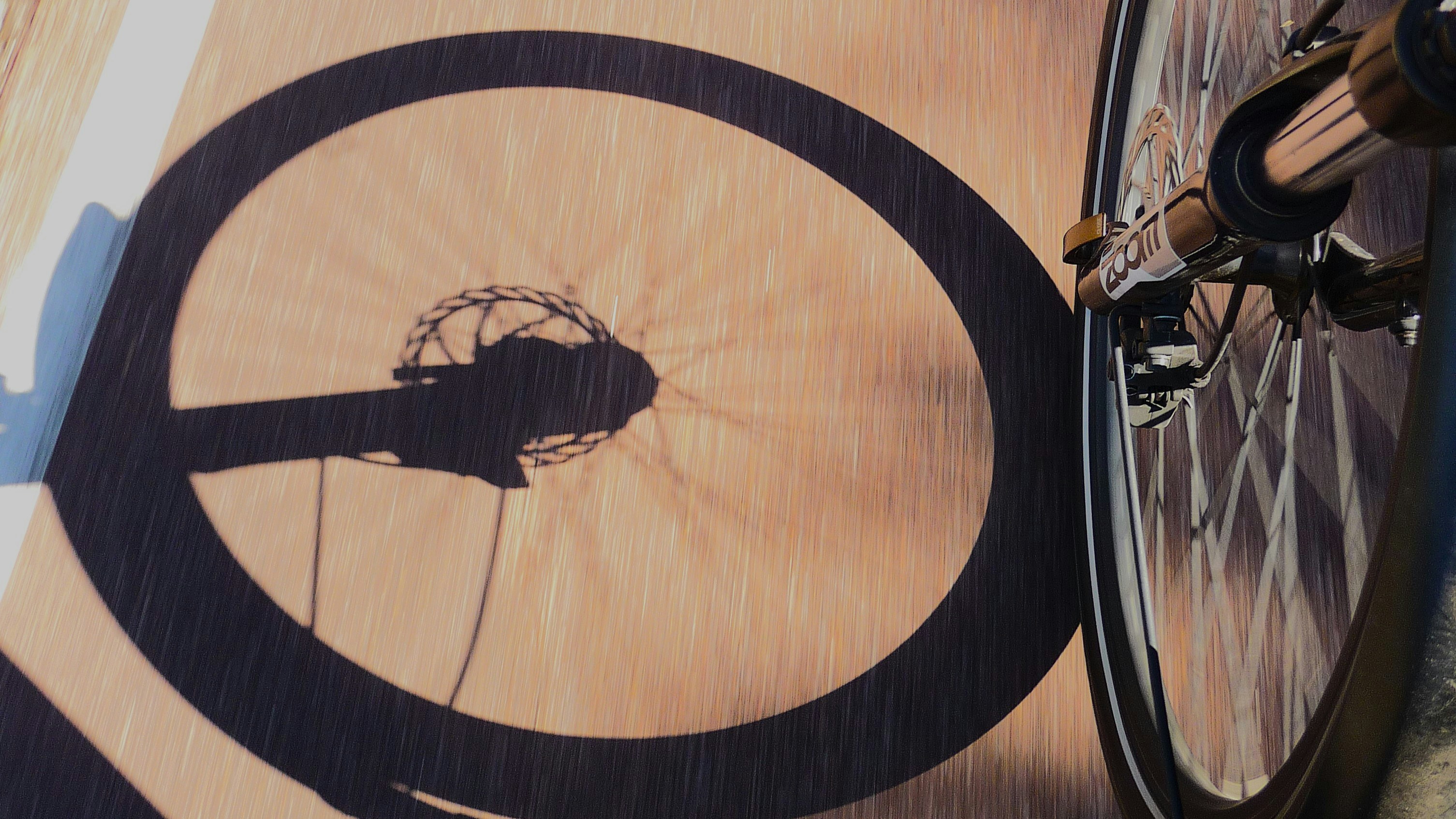 Sombra de uma roda de bicicleta sobre uma superfície de madeira