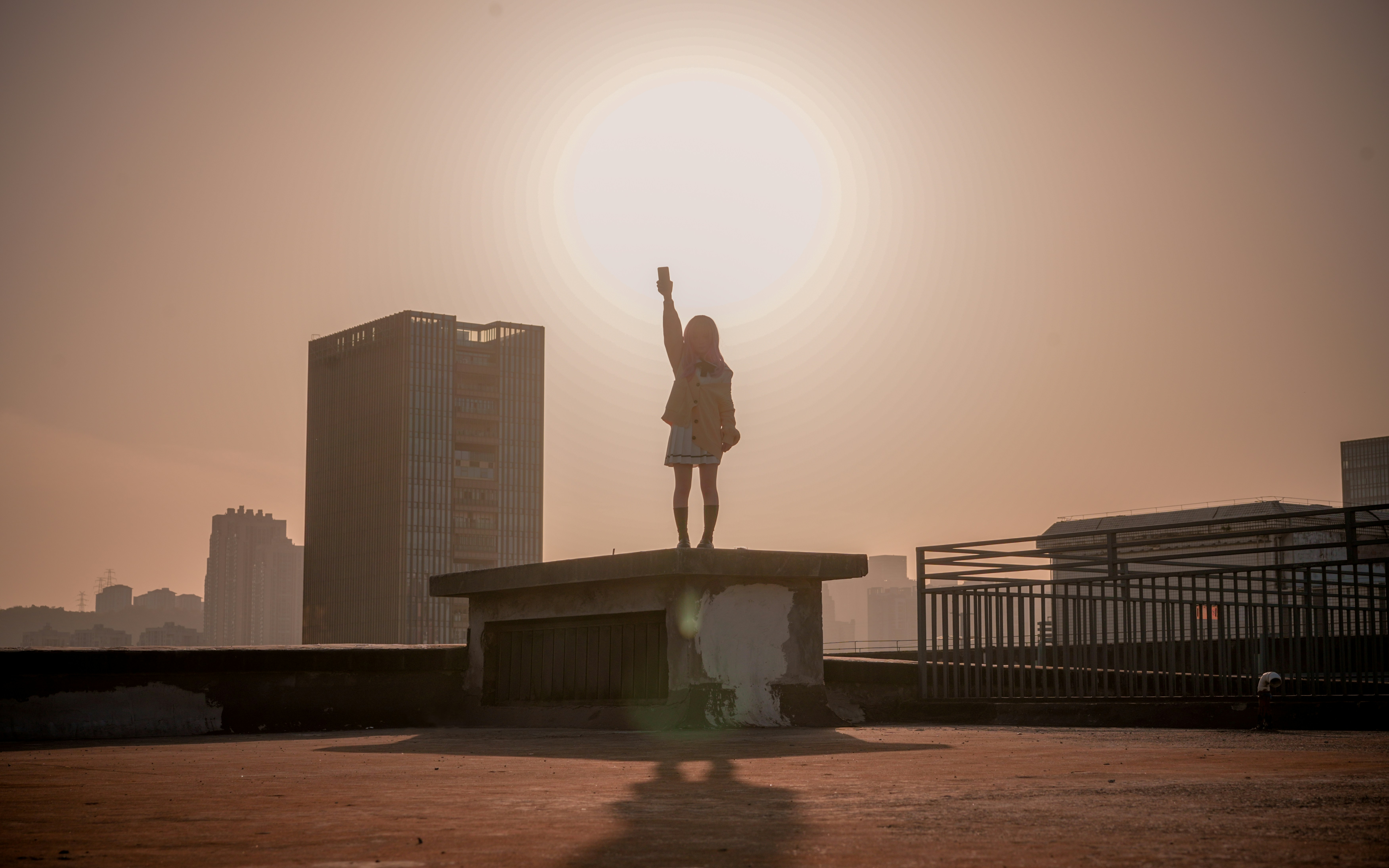Woman with arm raised on rooftop at sunset