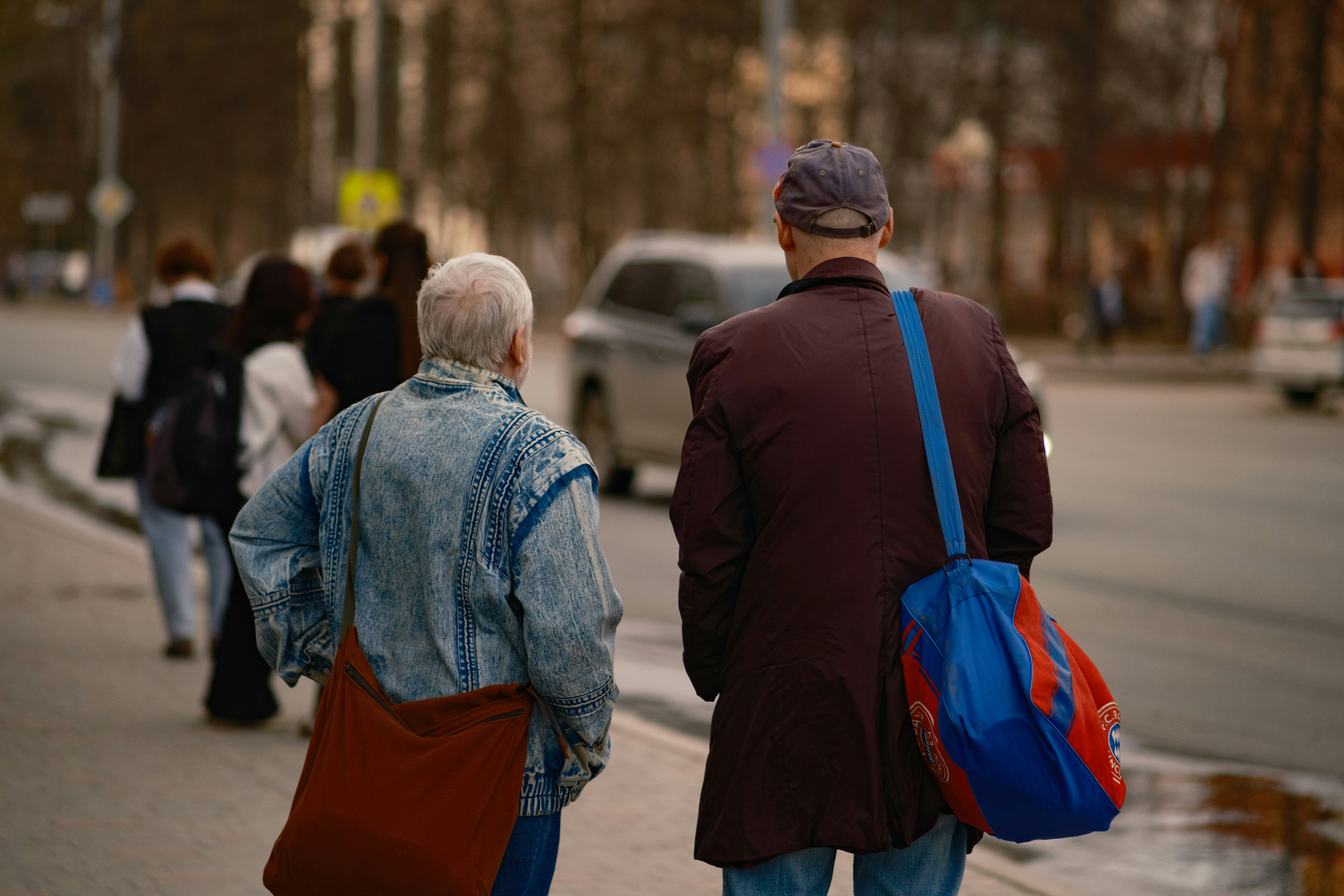 Two men walk down a sidewalk with others behind.