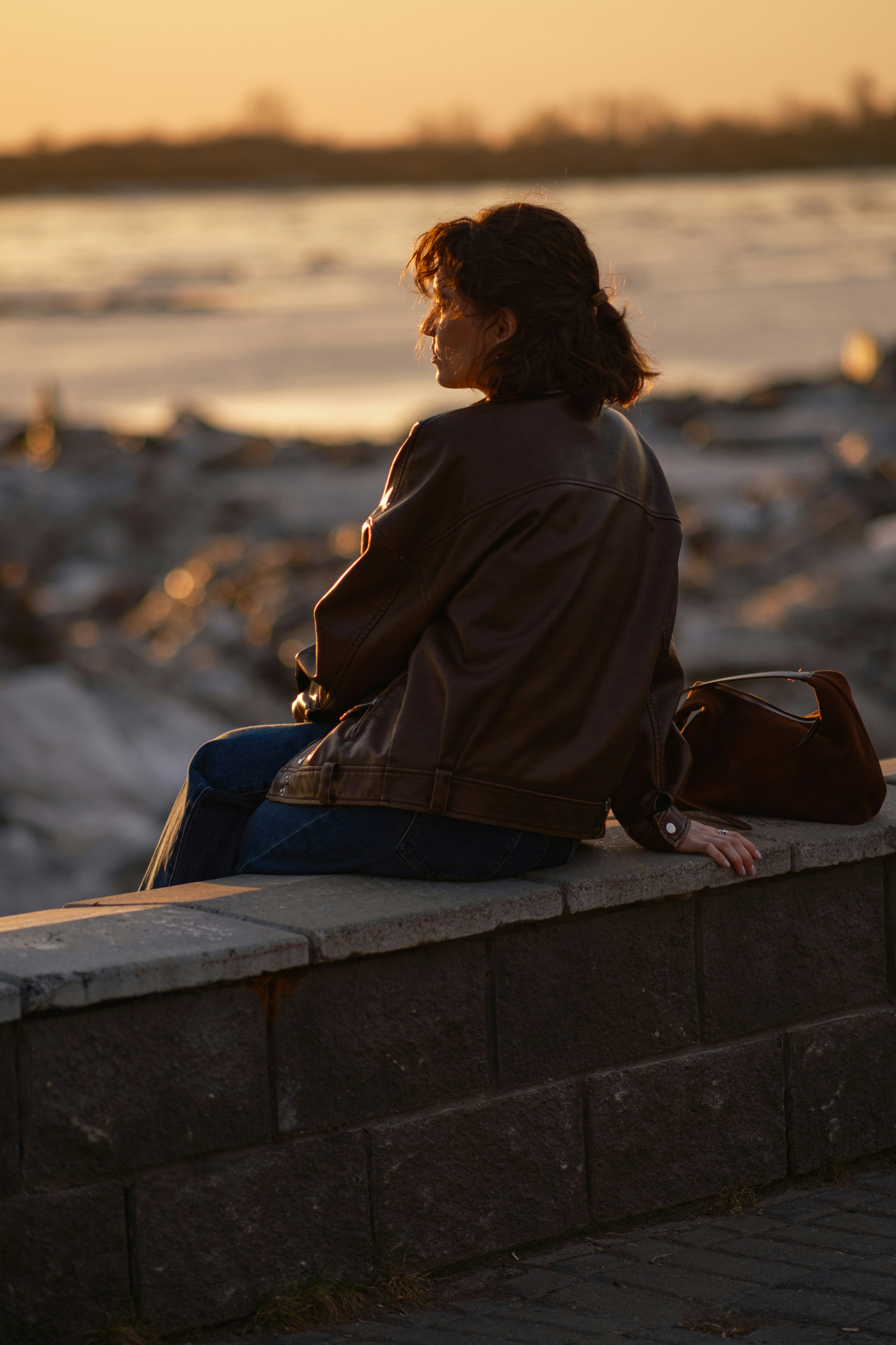 Woman sitting on a wall at sunset