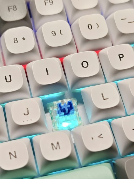 Close-up of a white mechanical keyboard showing individual switches and keycaps