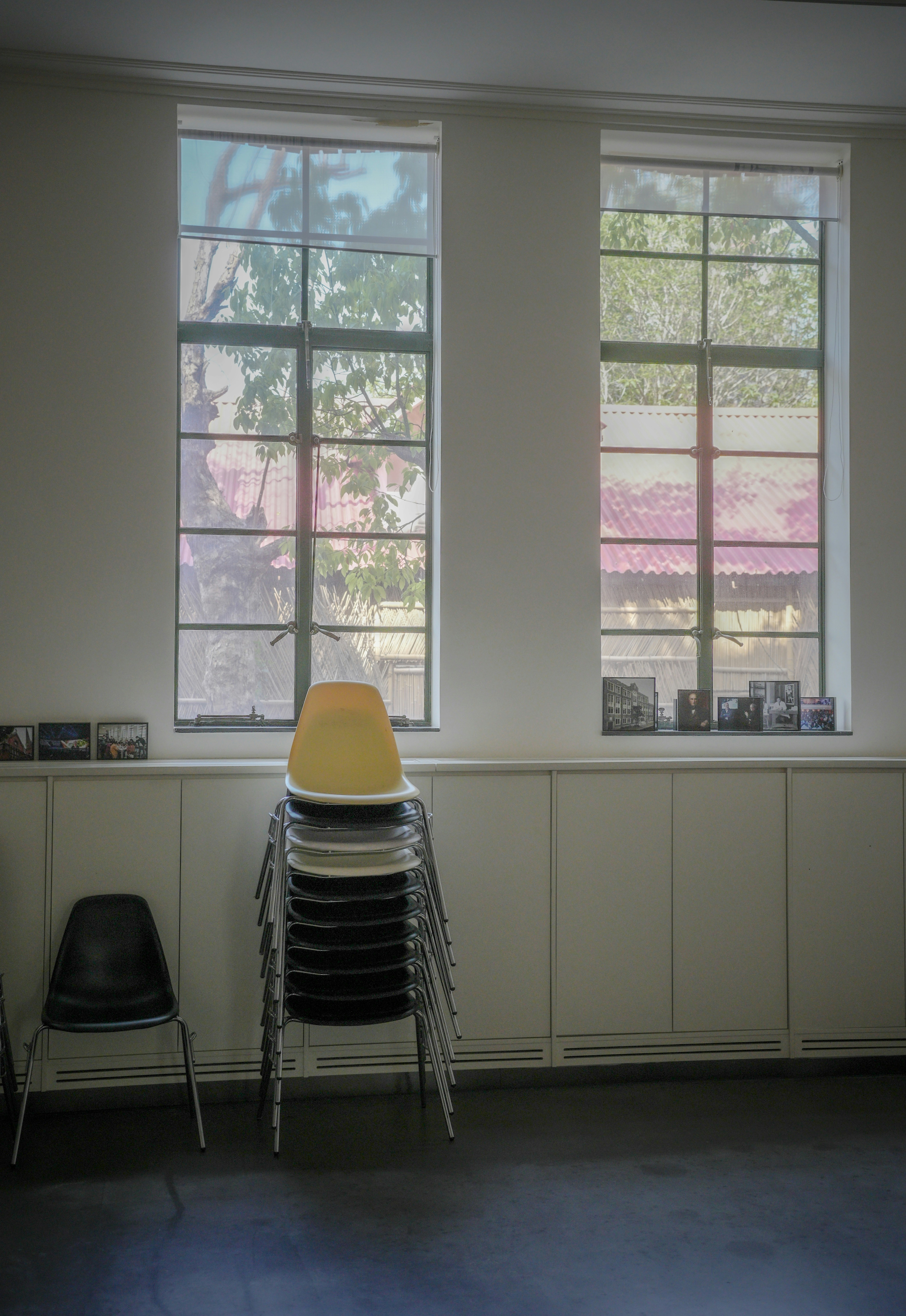 Stack of chairs in front of two large windows.