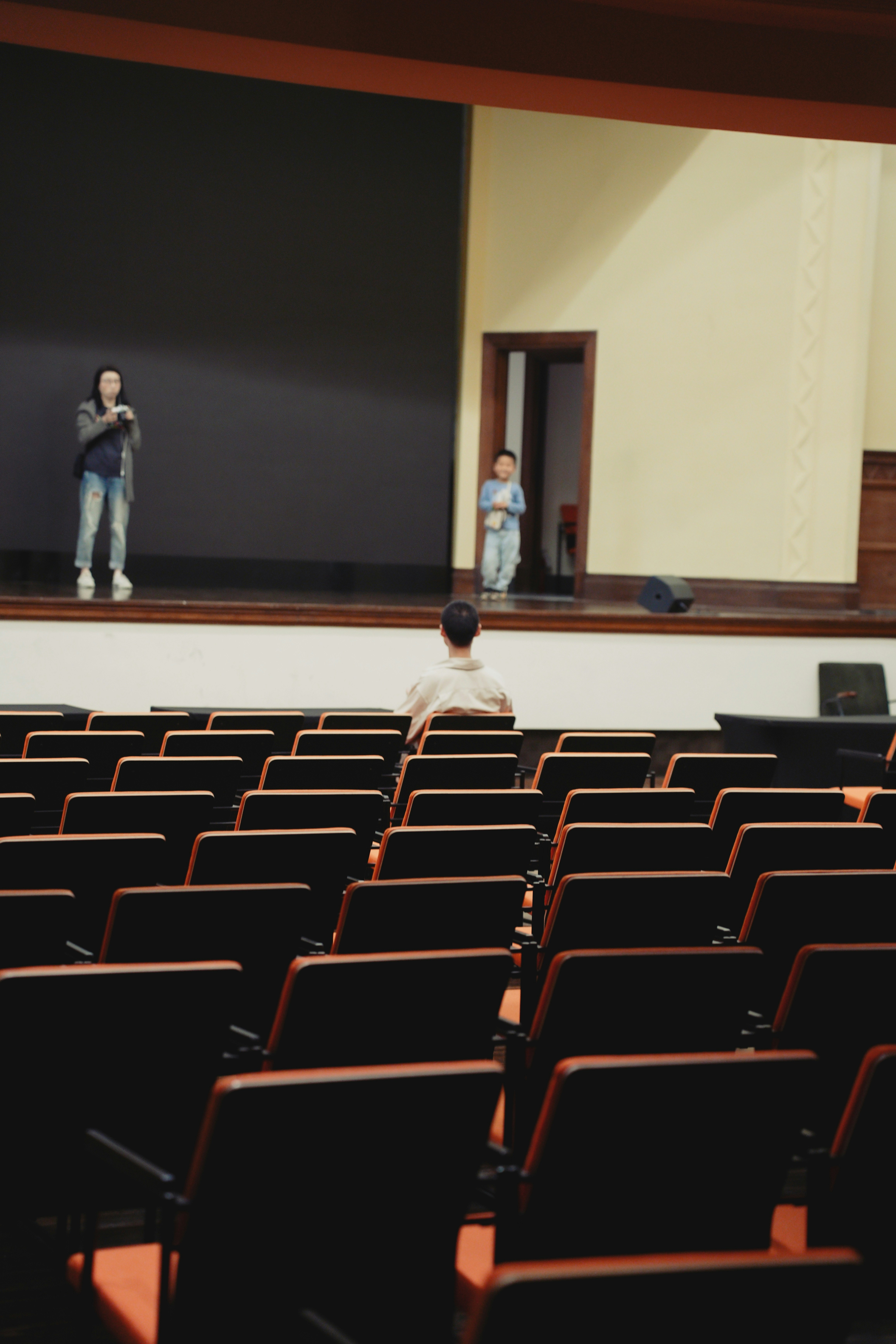Duas pessoas no palco em um auditório vazio.