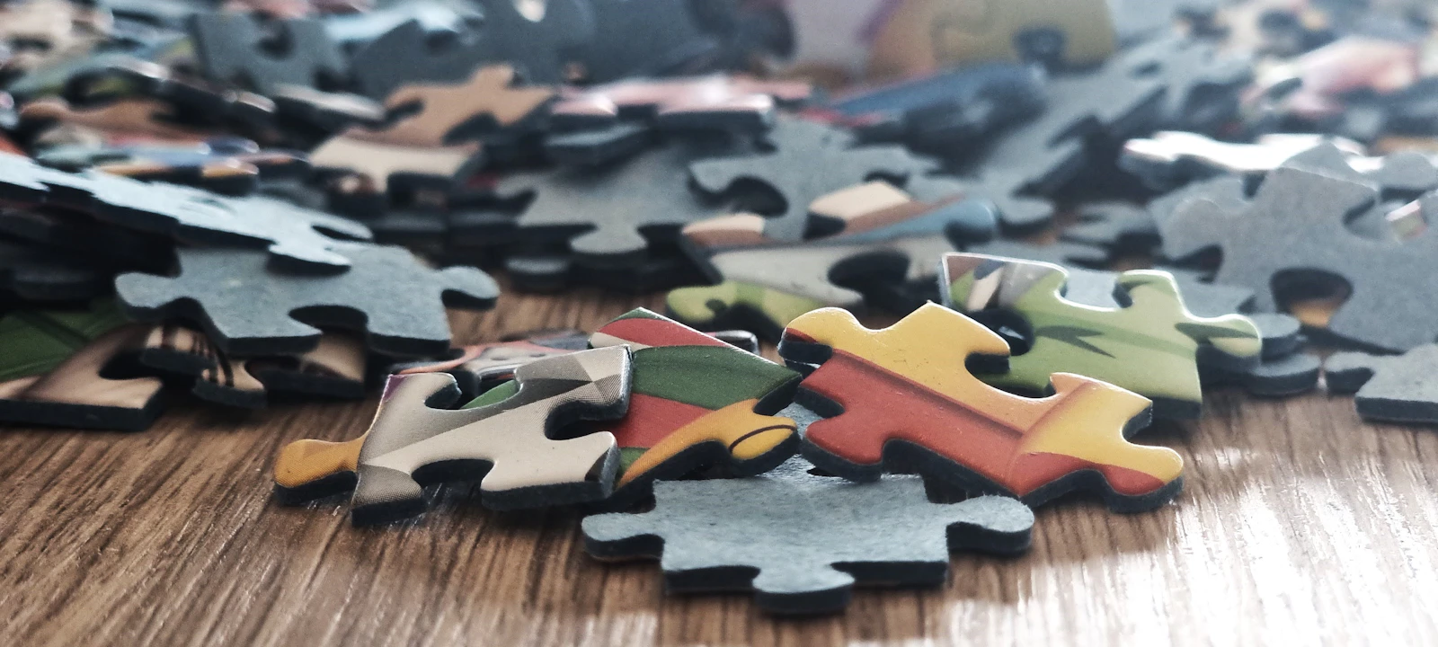 Scattered colorful puzzle pieces on a wooden surface
