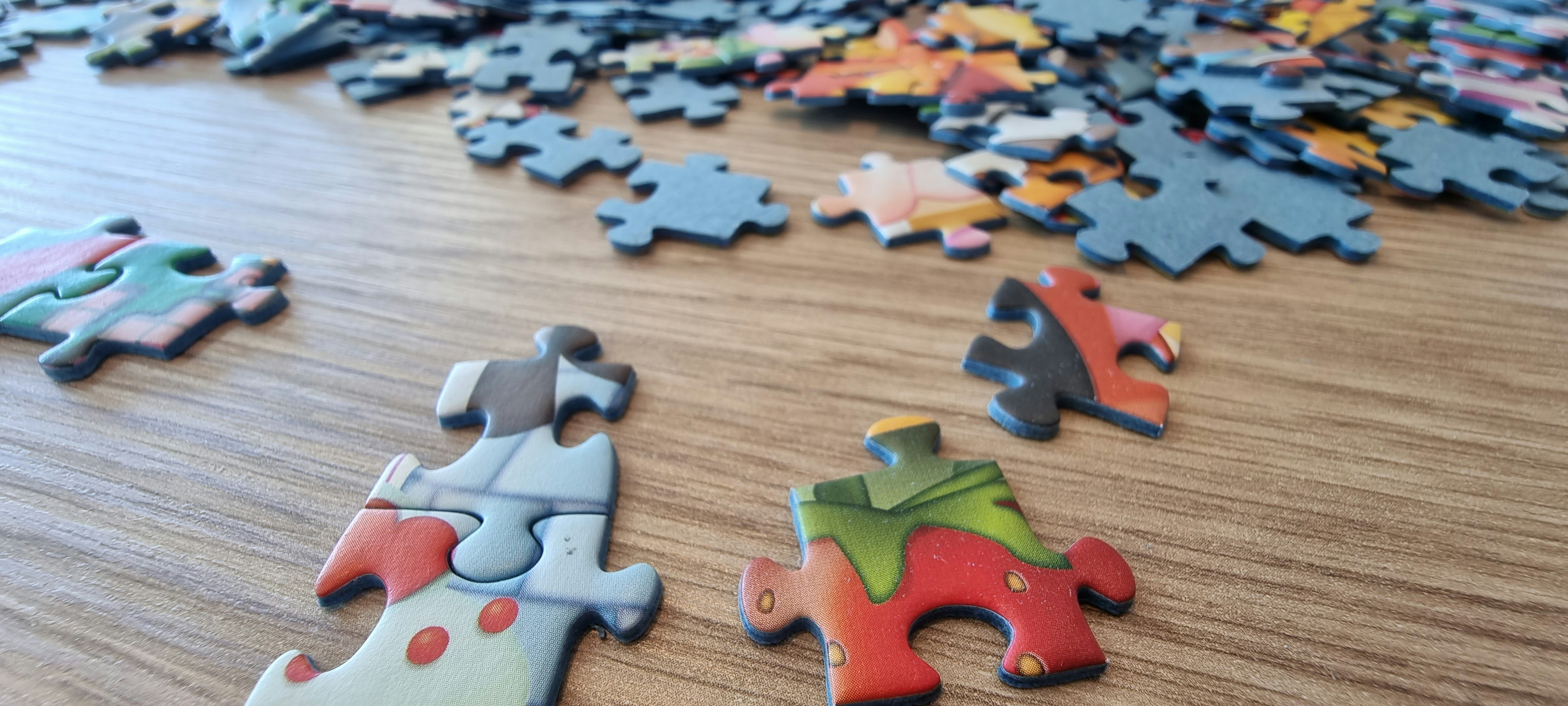 Scattered puzzle pieces on a wooden surface.
