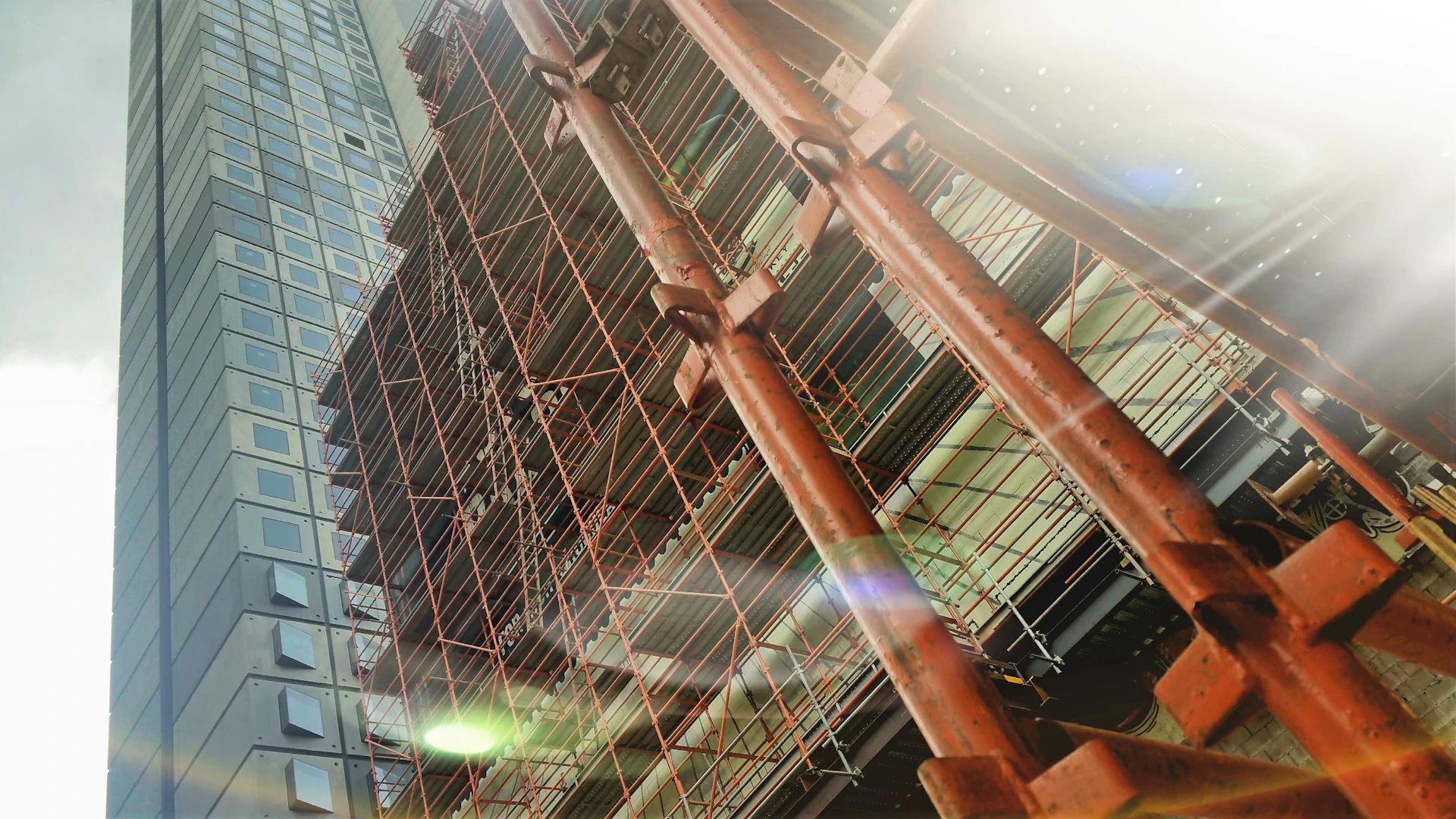Skyscraper under construction with orange scaffolding