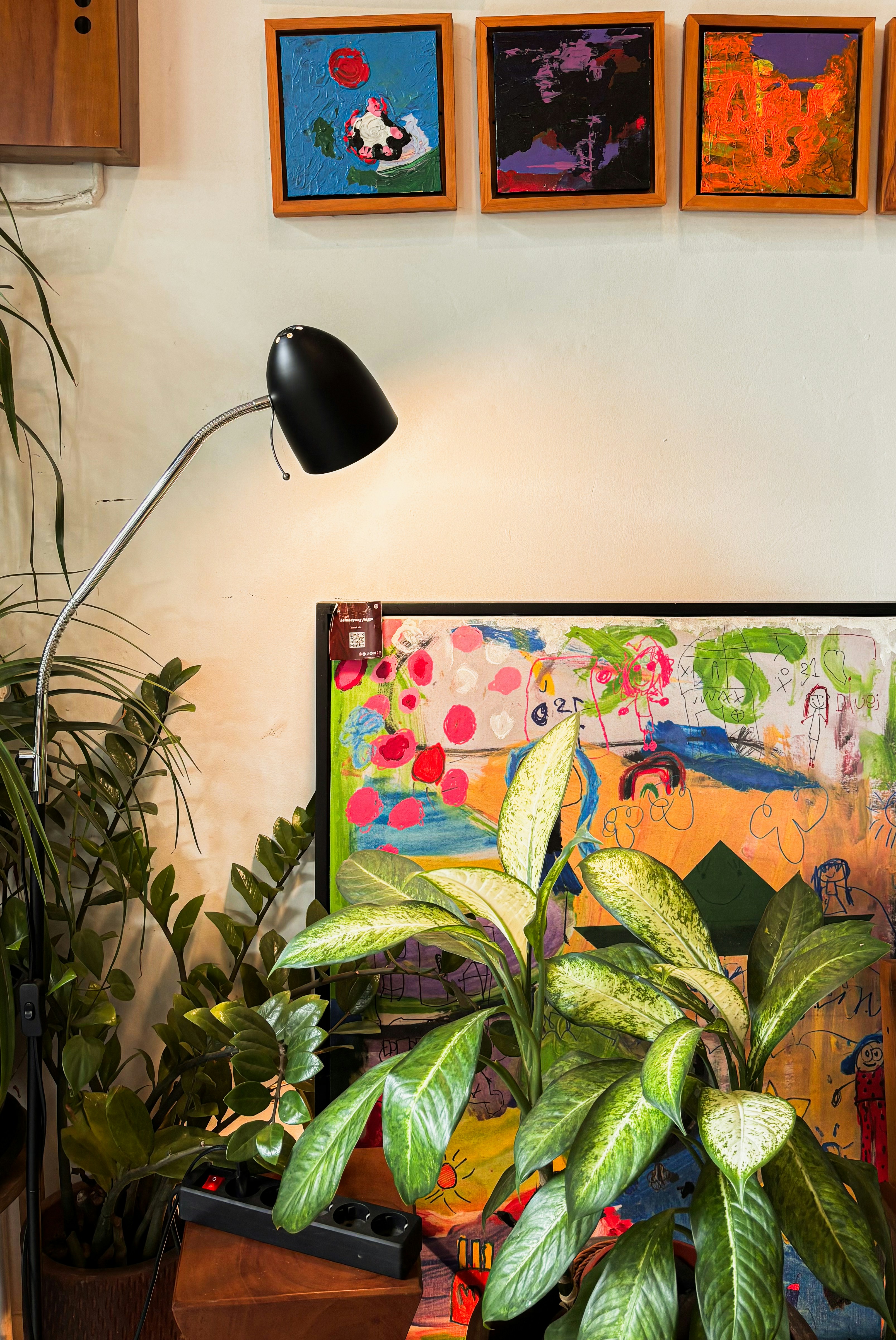 Plants and colorful artwork displayed on a wall.