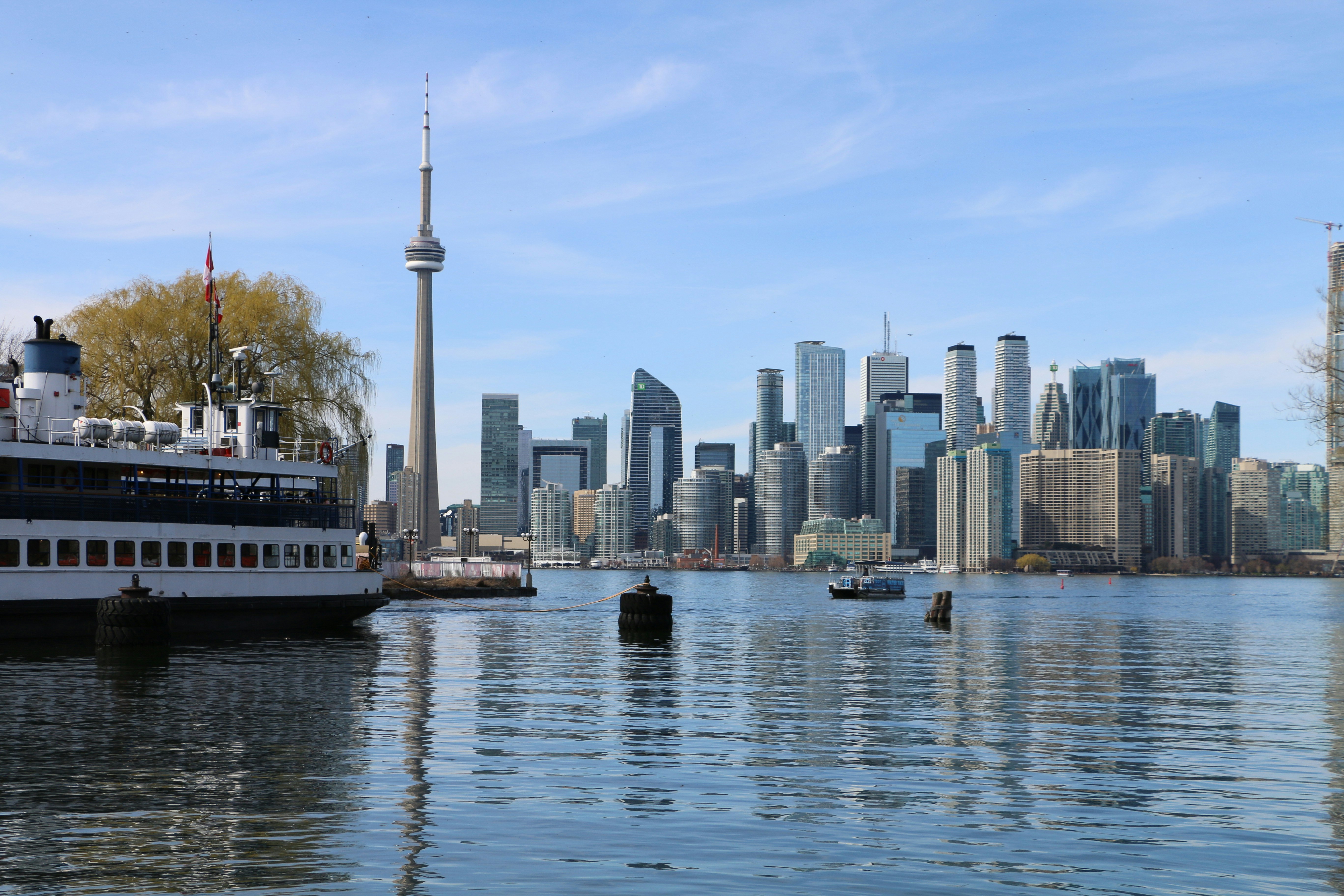 Toronto skyline with cn tower and ferry on water.