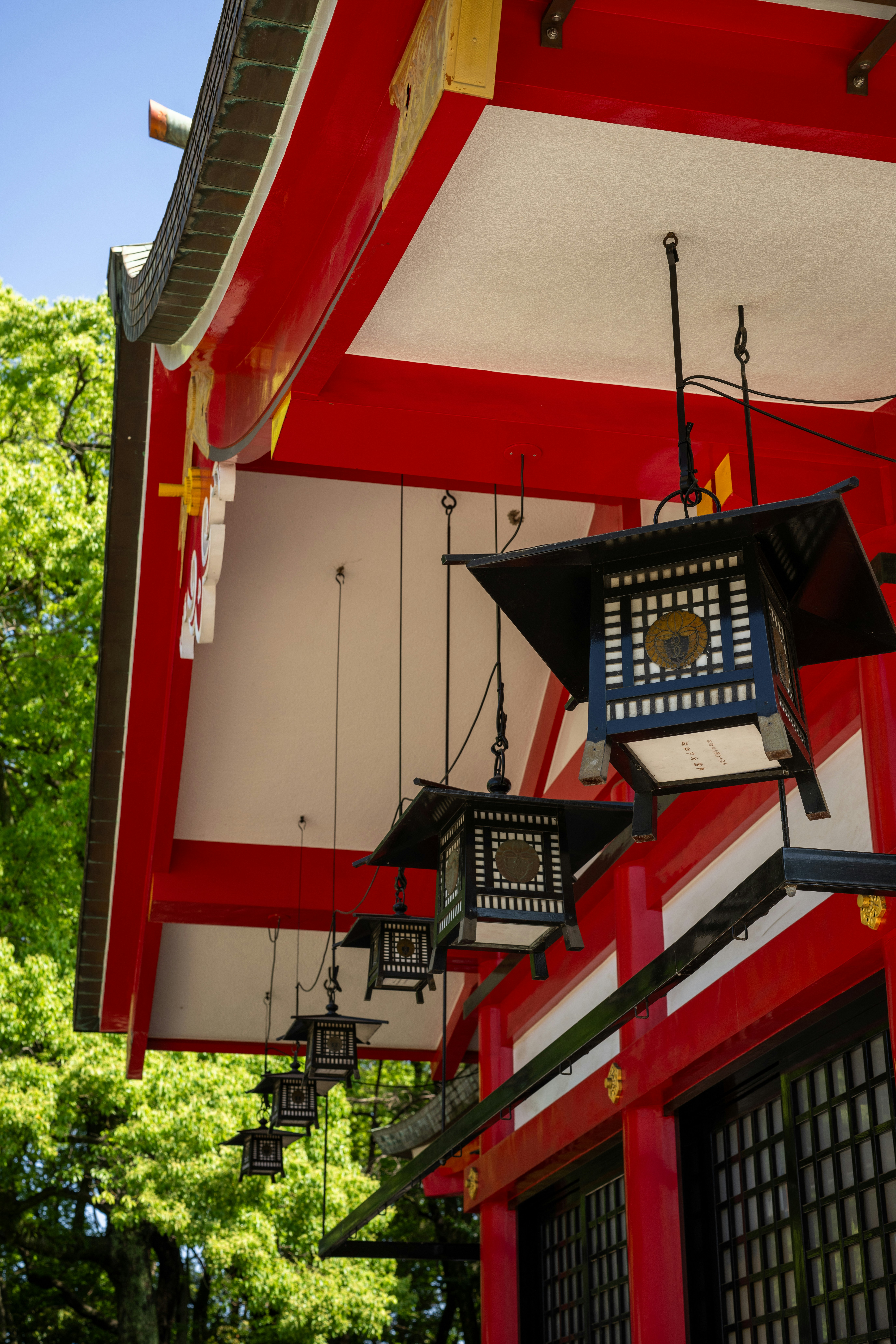 Traditional japanese lanterns hang outside a red and white temple.