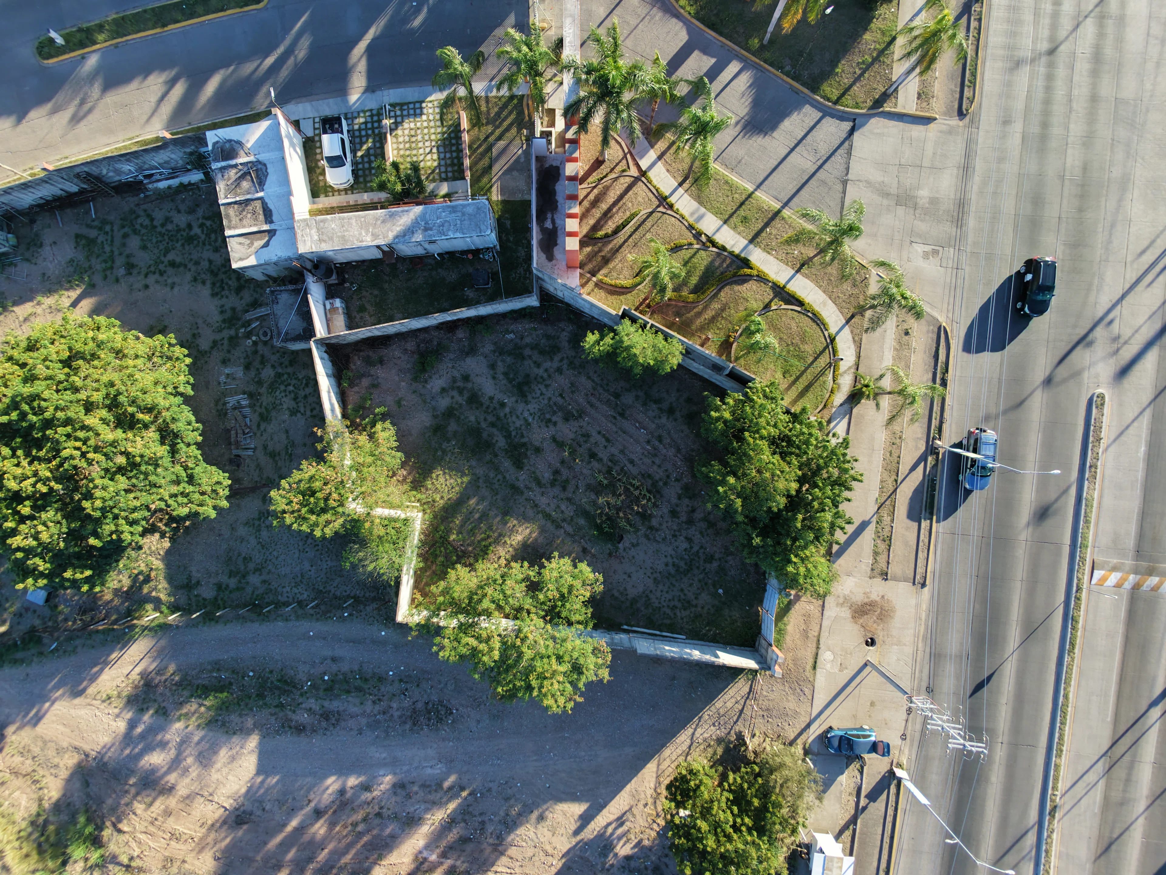 Aerial view of an empty plot beside a paved street