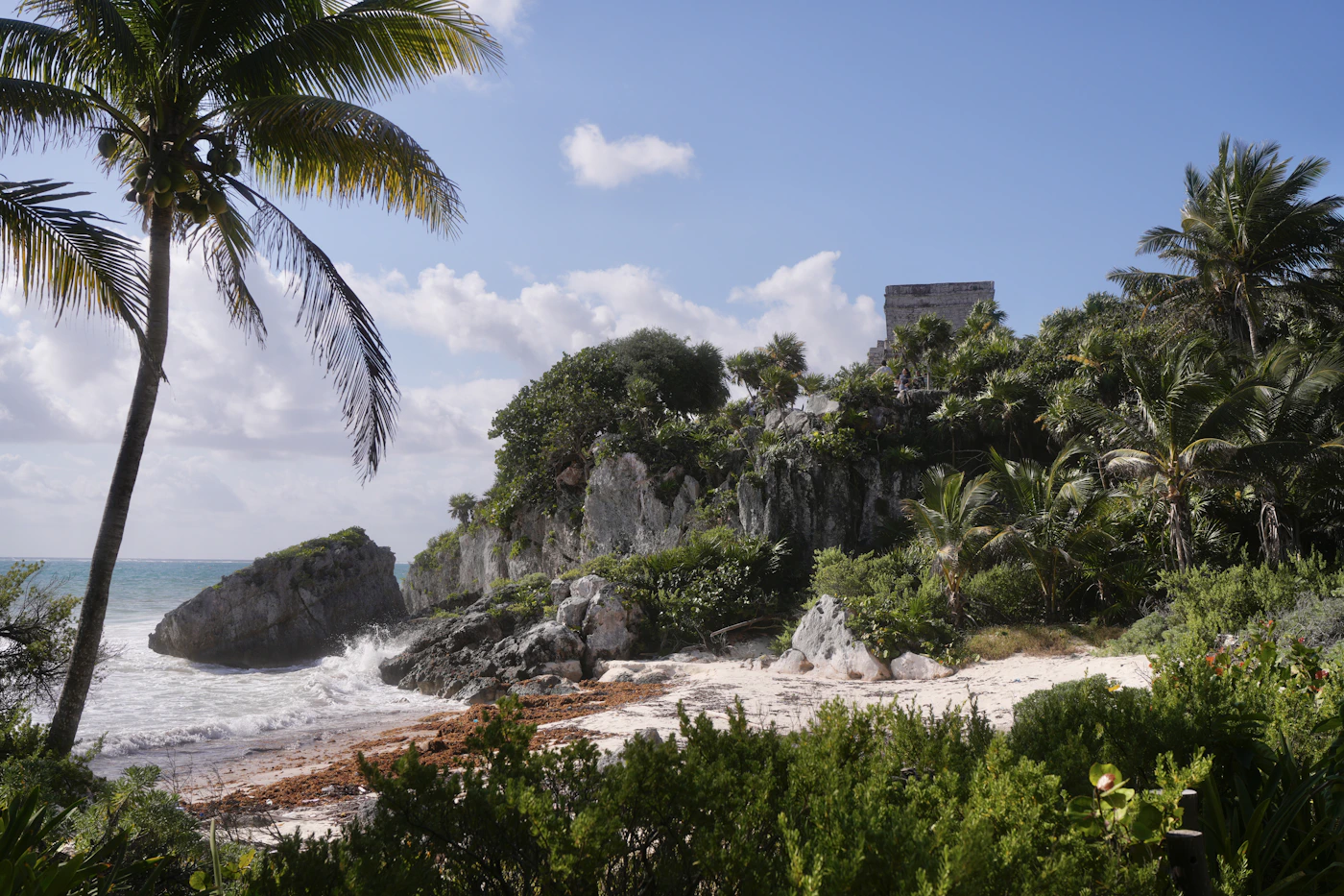 Ancient Mayan ruins on a cliff overlooking the turquoise Caribbean Sea at Tulum Quintana Roo Mexico with the archaeological site visible above the beach
