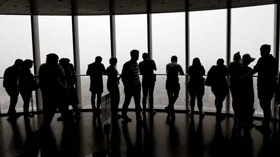 Visitors silhouetted against floor-to-ceiling windows at the Shanghai Tower observation deck, overlooking the city