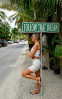 Woman leans against pole under "follow that dream" sign
