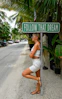 Woman leans against pole under "follow that dream" sign