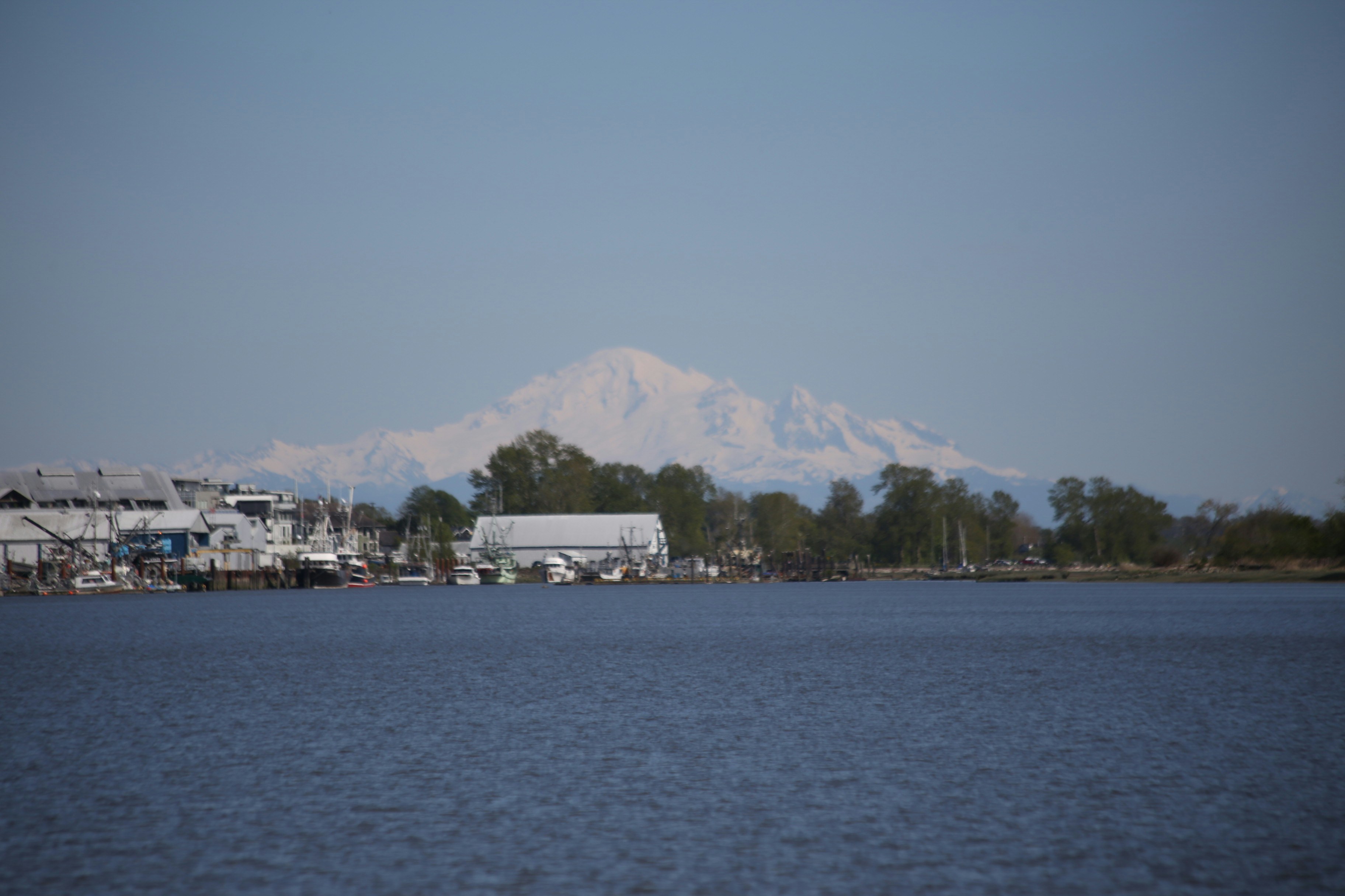 Snow-capped mountains rise behind a coastal town.