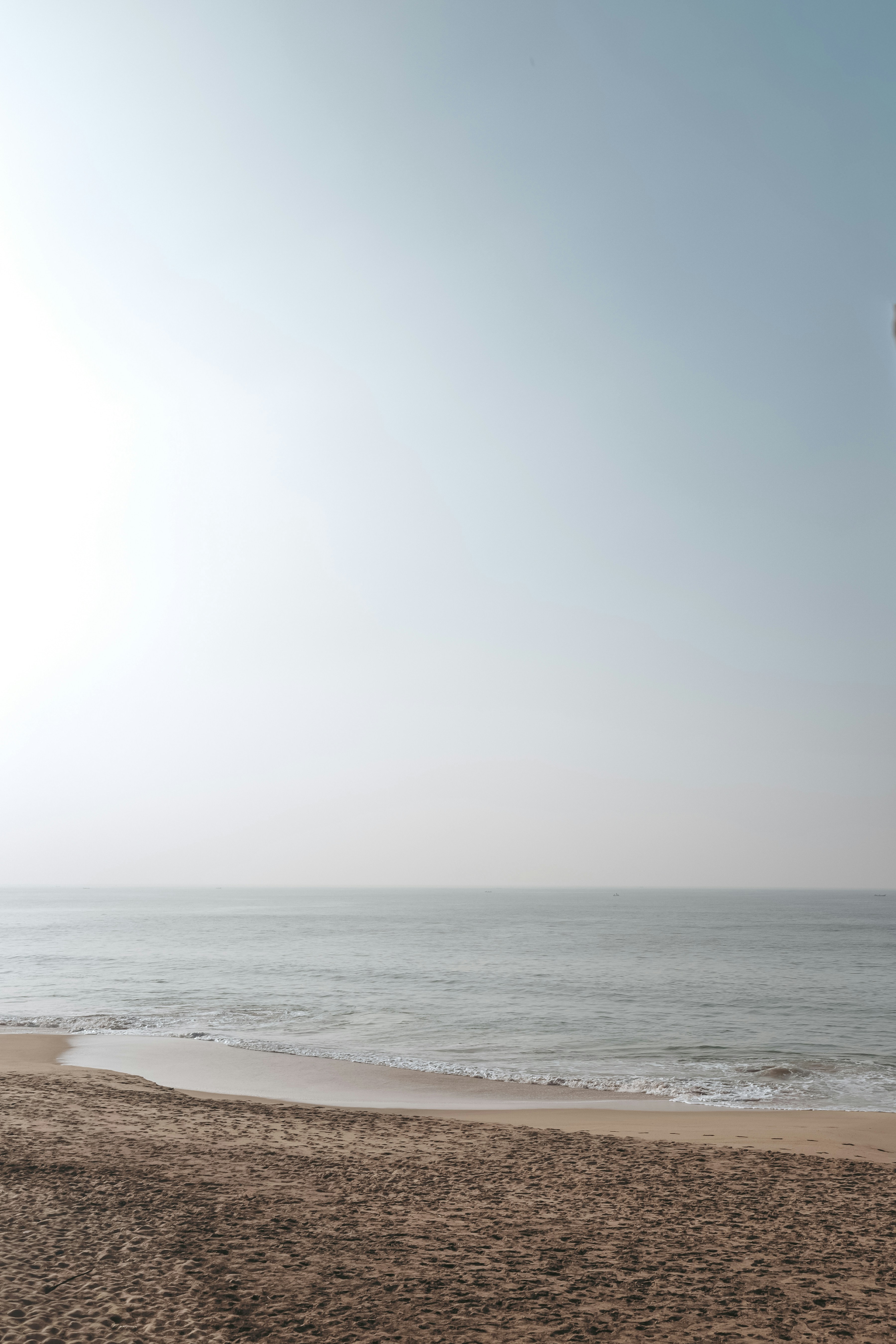 Praia de areia encontra um oceano calmo sob um céu claro