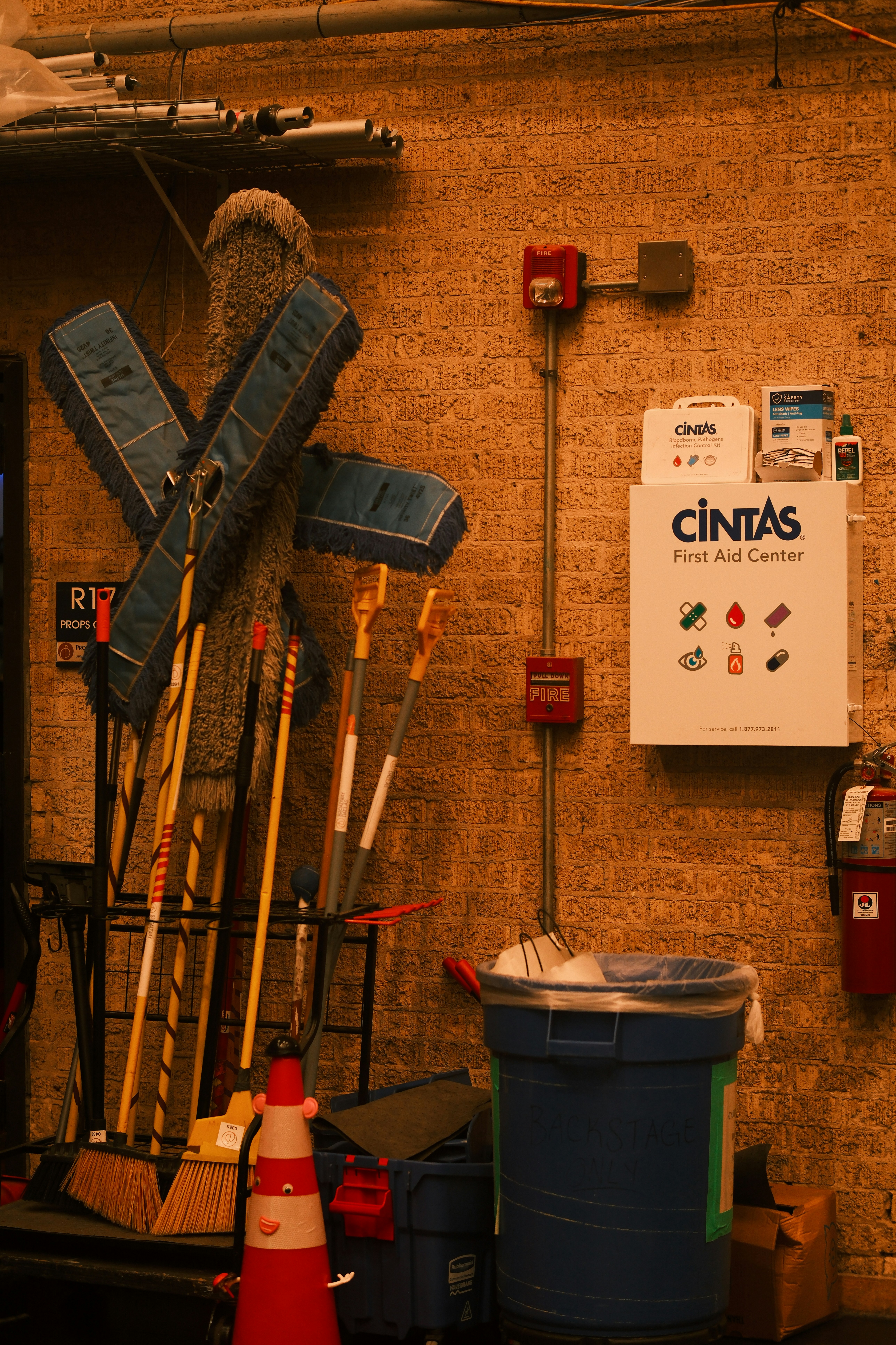 Cleaning supplies and first aid kit on brick wall.