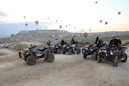 People on atvs with hot air balloons in the sky