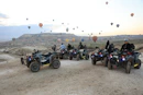 People on atvs with hot air balloons in the sky