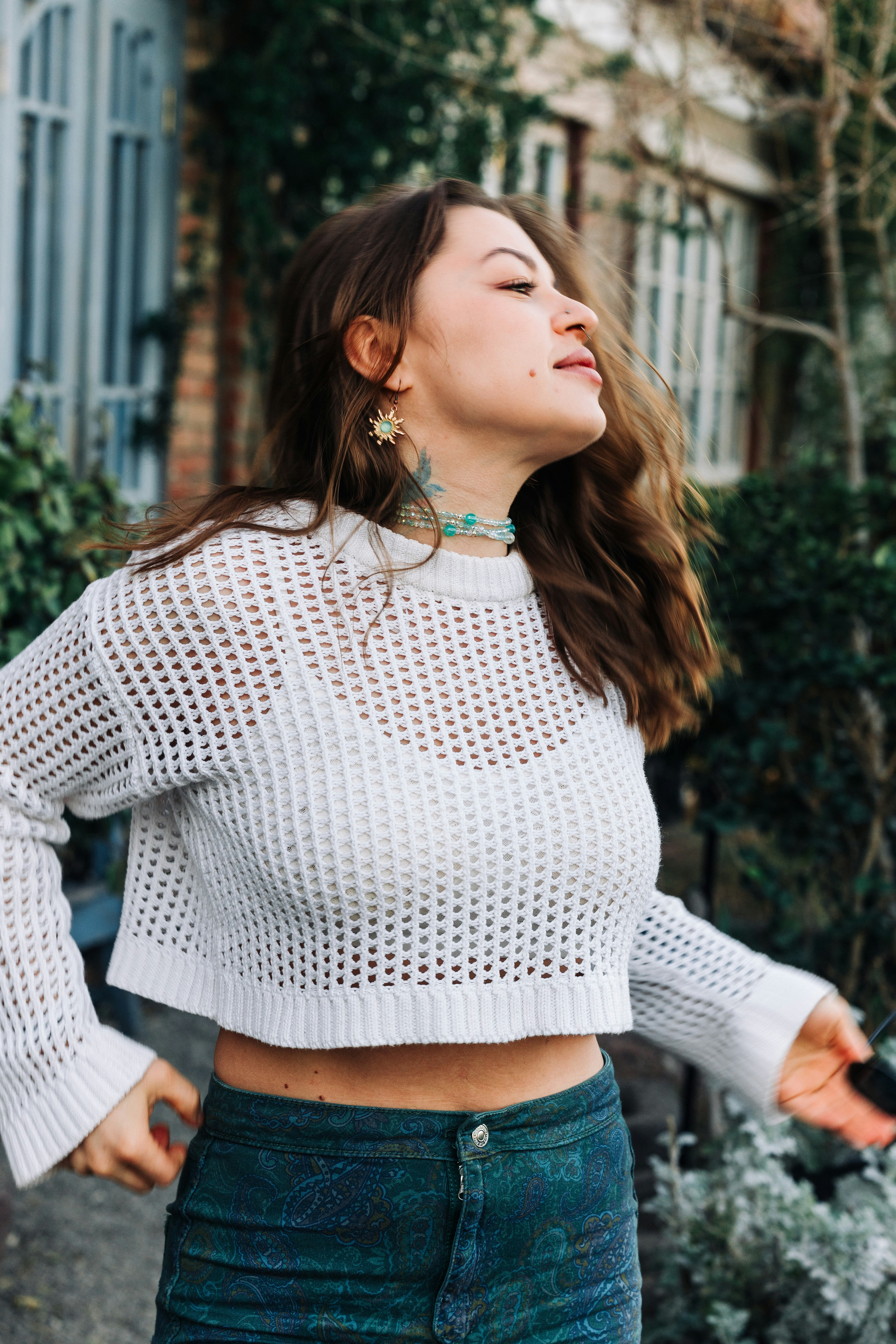 Une jeune femme en pull blanc et pantalon à motifs.