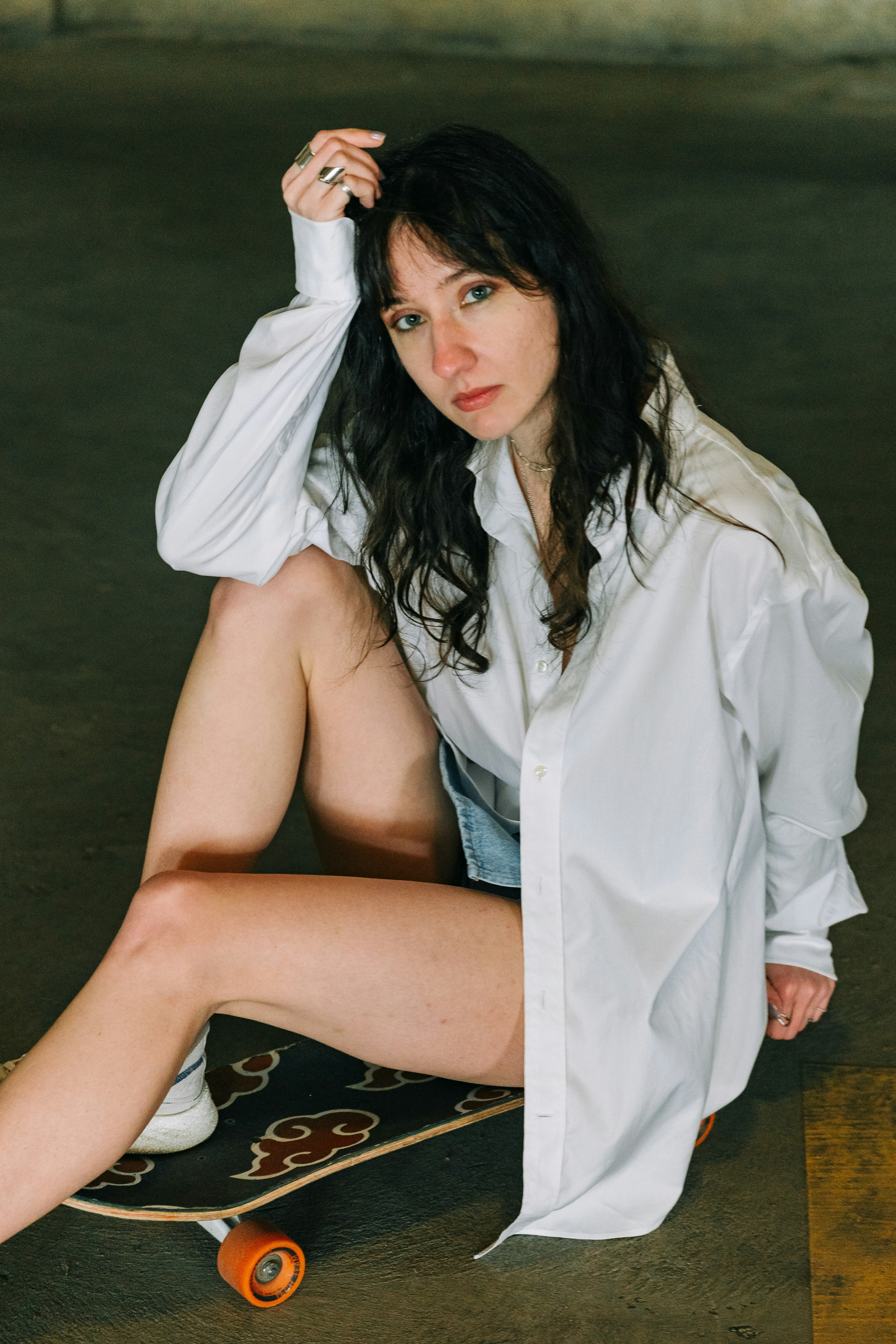 Young woman in white shirt sitting on skateboard
