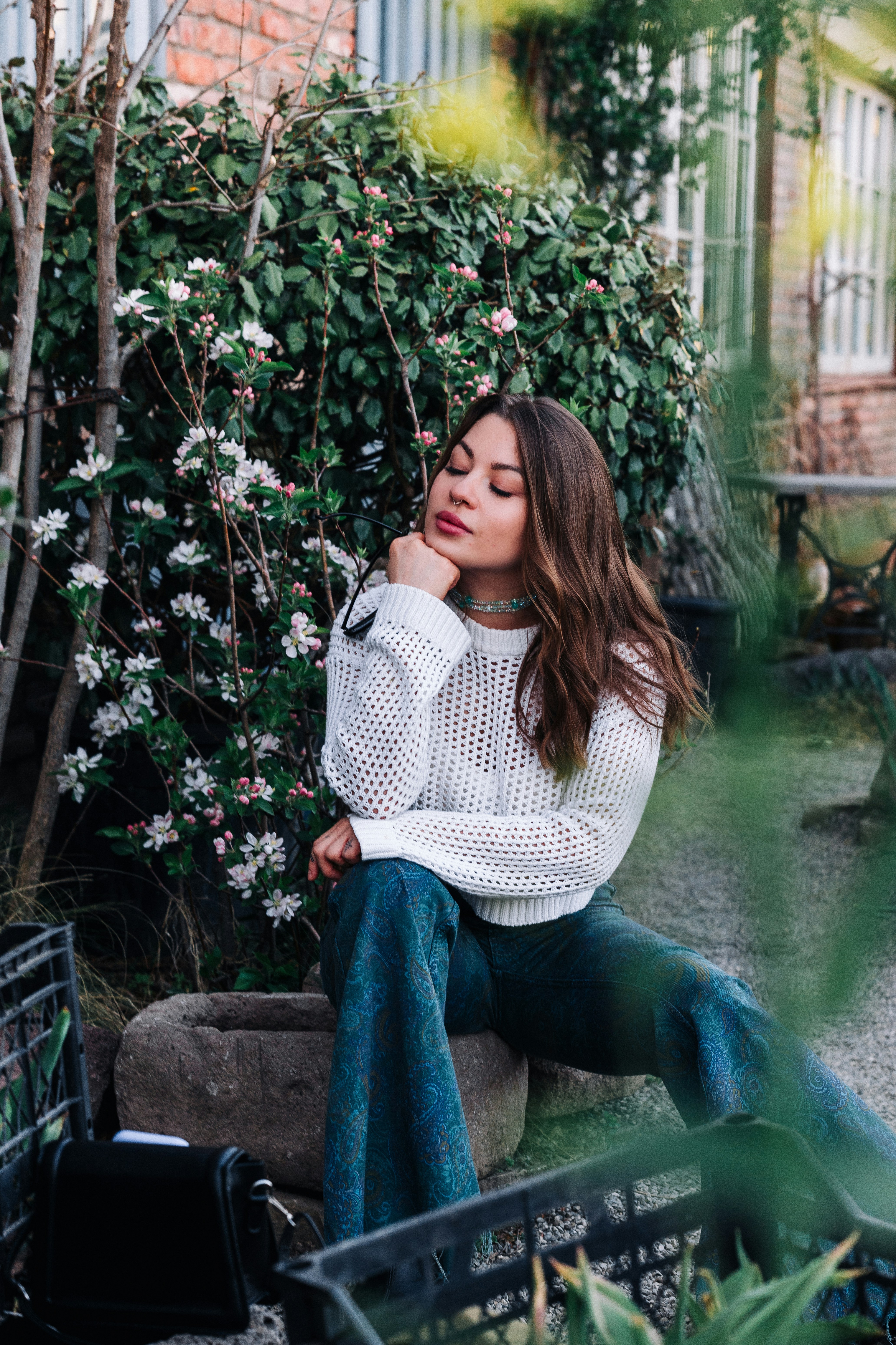 Woman sitting near blooming bushes in a garden.