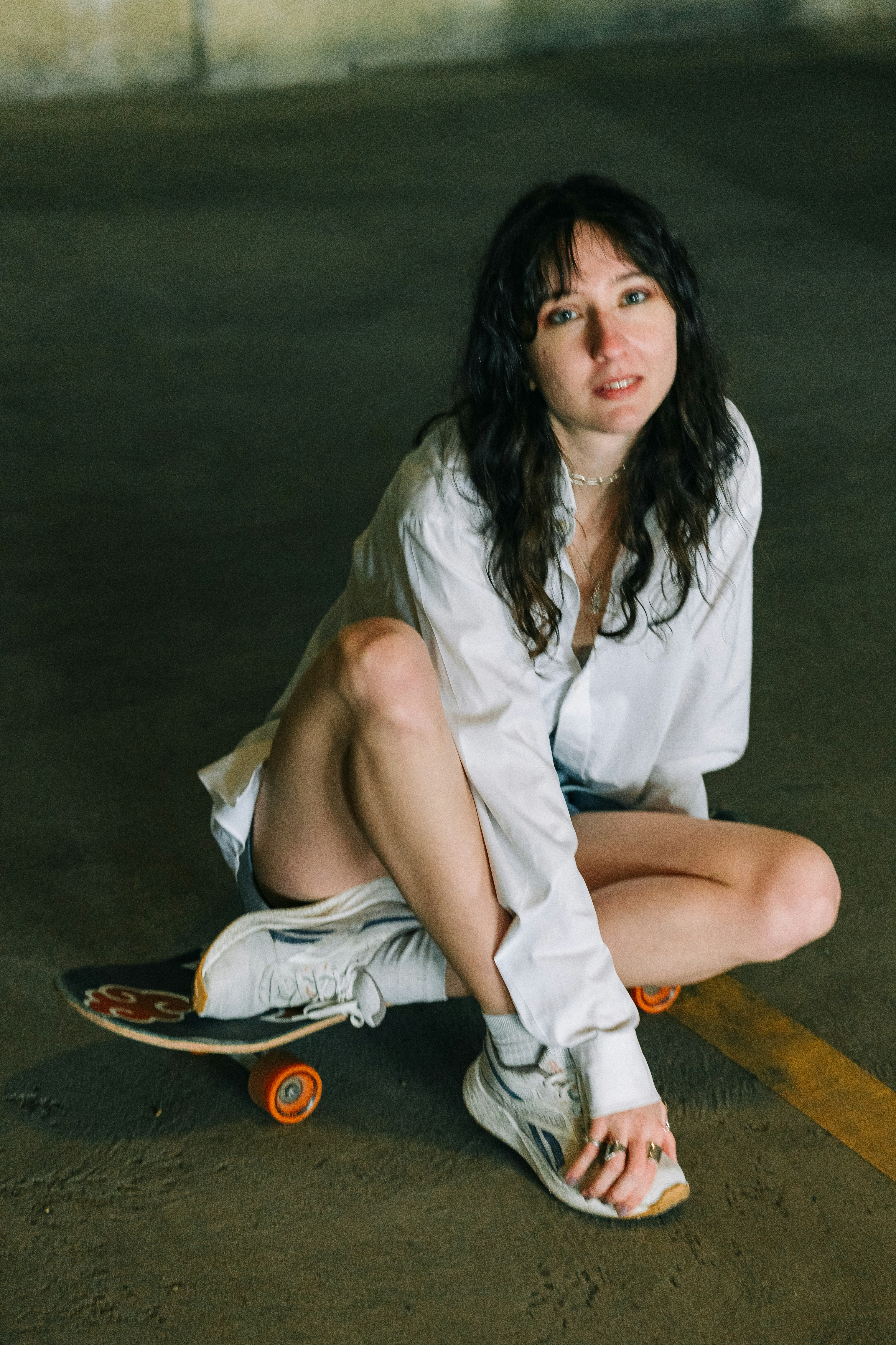 Jeune femme assise sur un skateboard à l’intérieur.