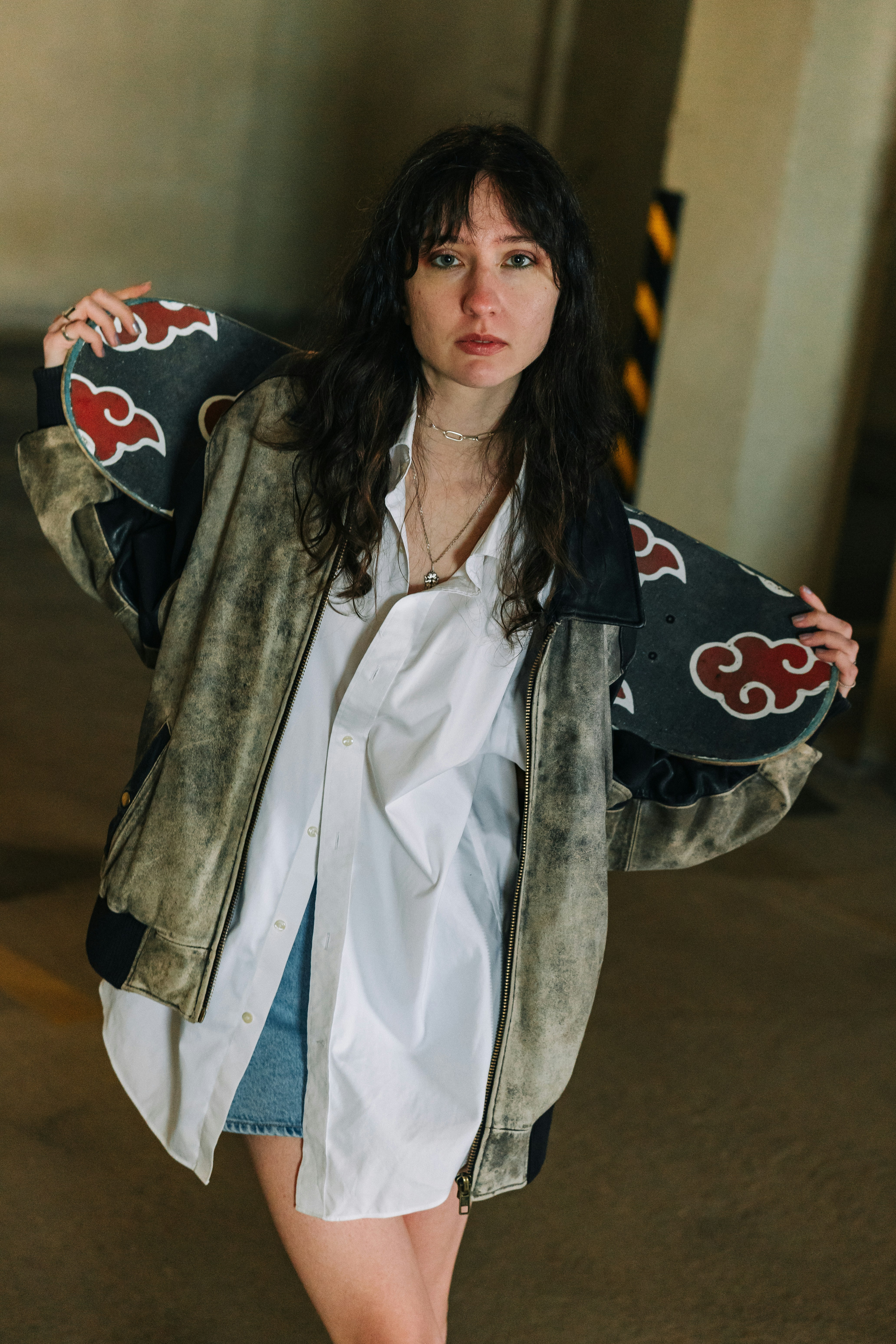 Jeune femme tenant un skateboard avec des nuages rouges
