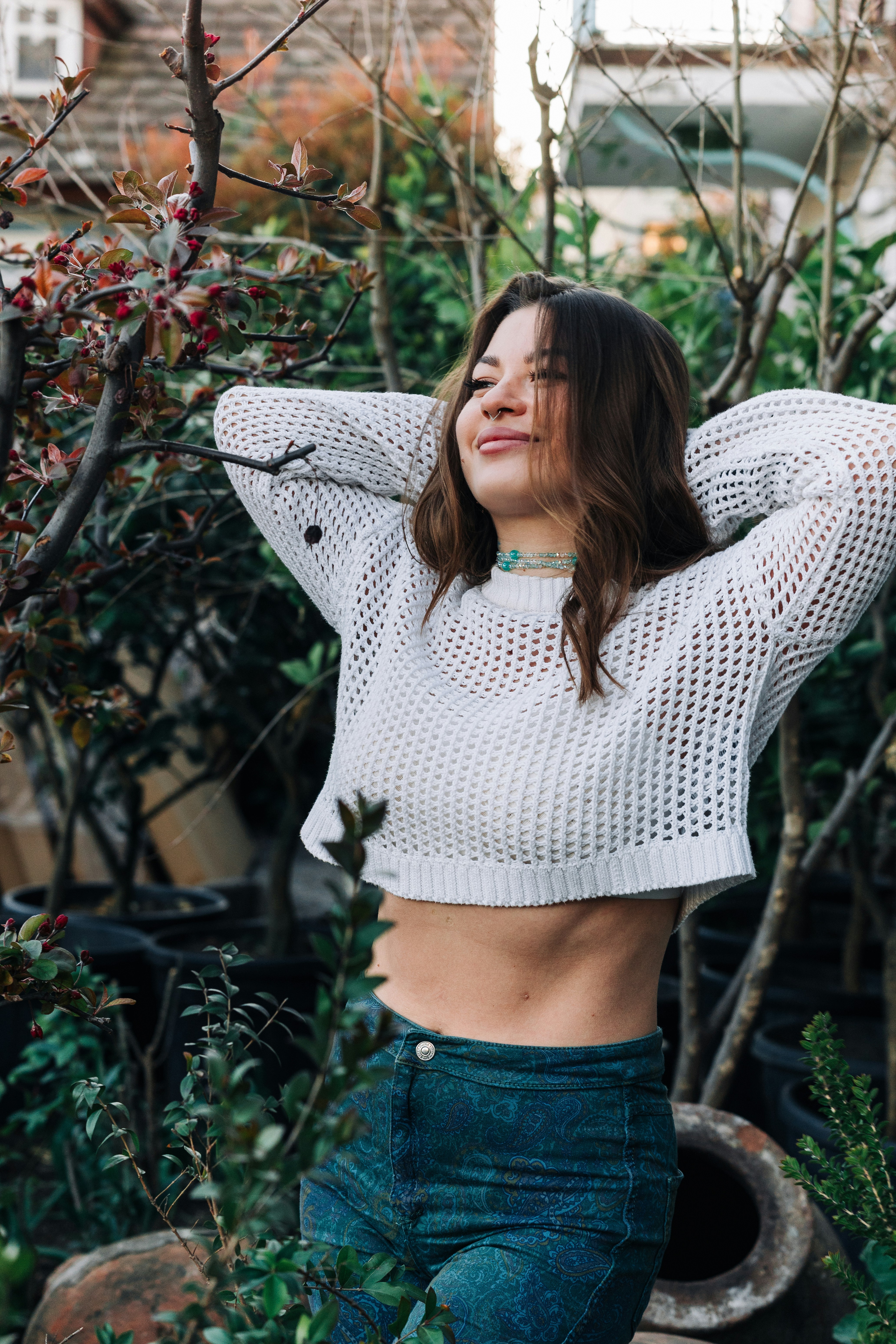 Jeune femme les mains derrière la tête dans le jardin