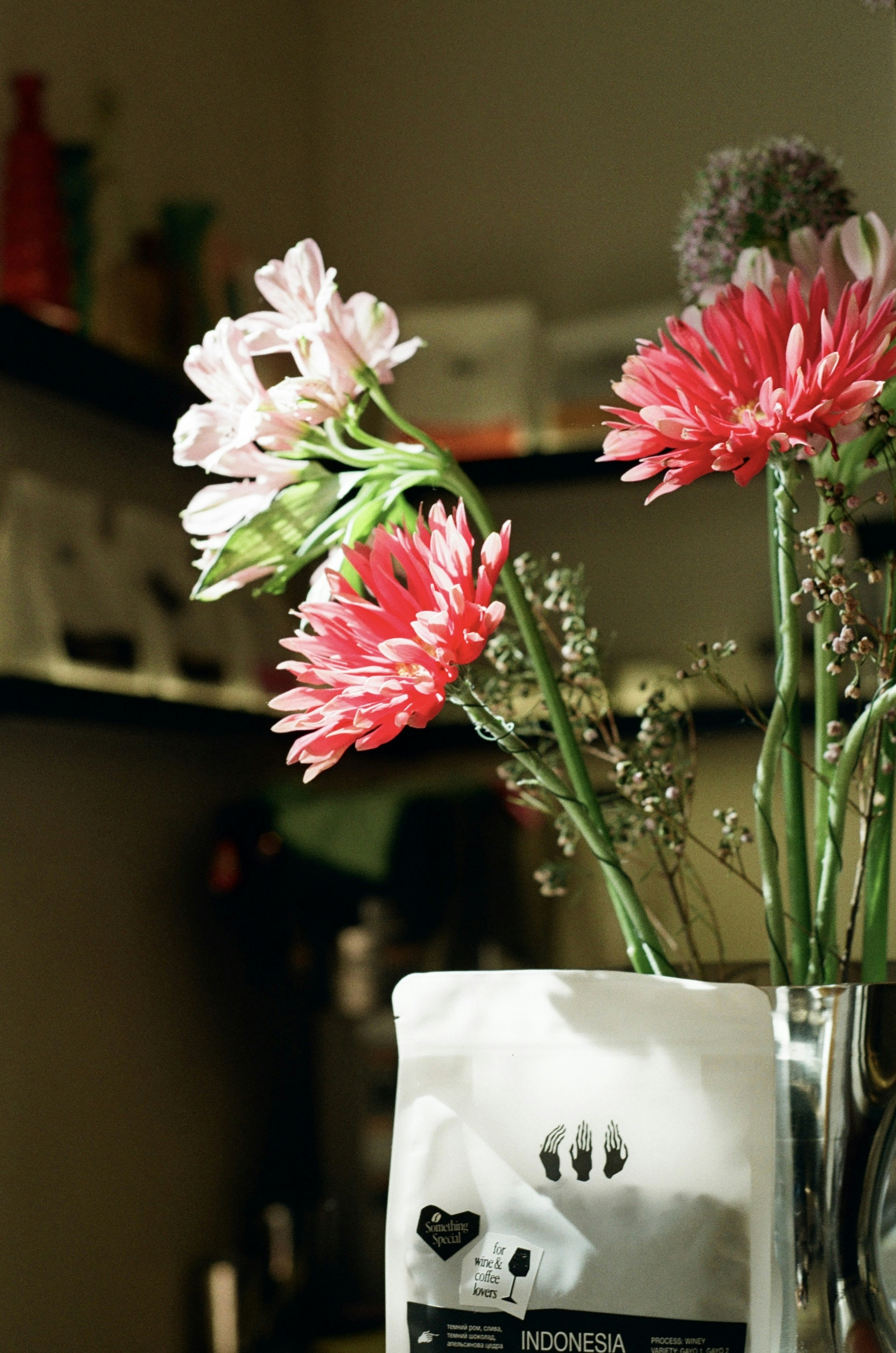 Pink and red gerbera daisies with greenery and coffee bag.