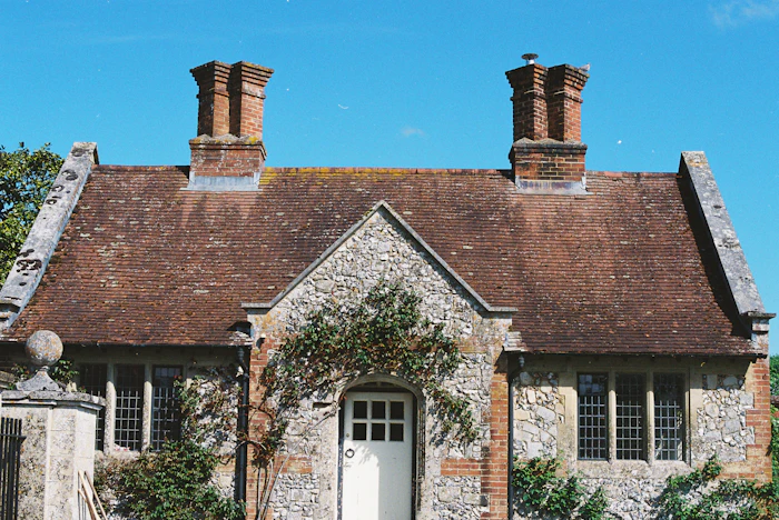 A stone cottage with a tiled roof and twin chimneys