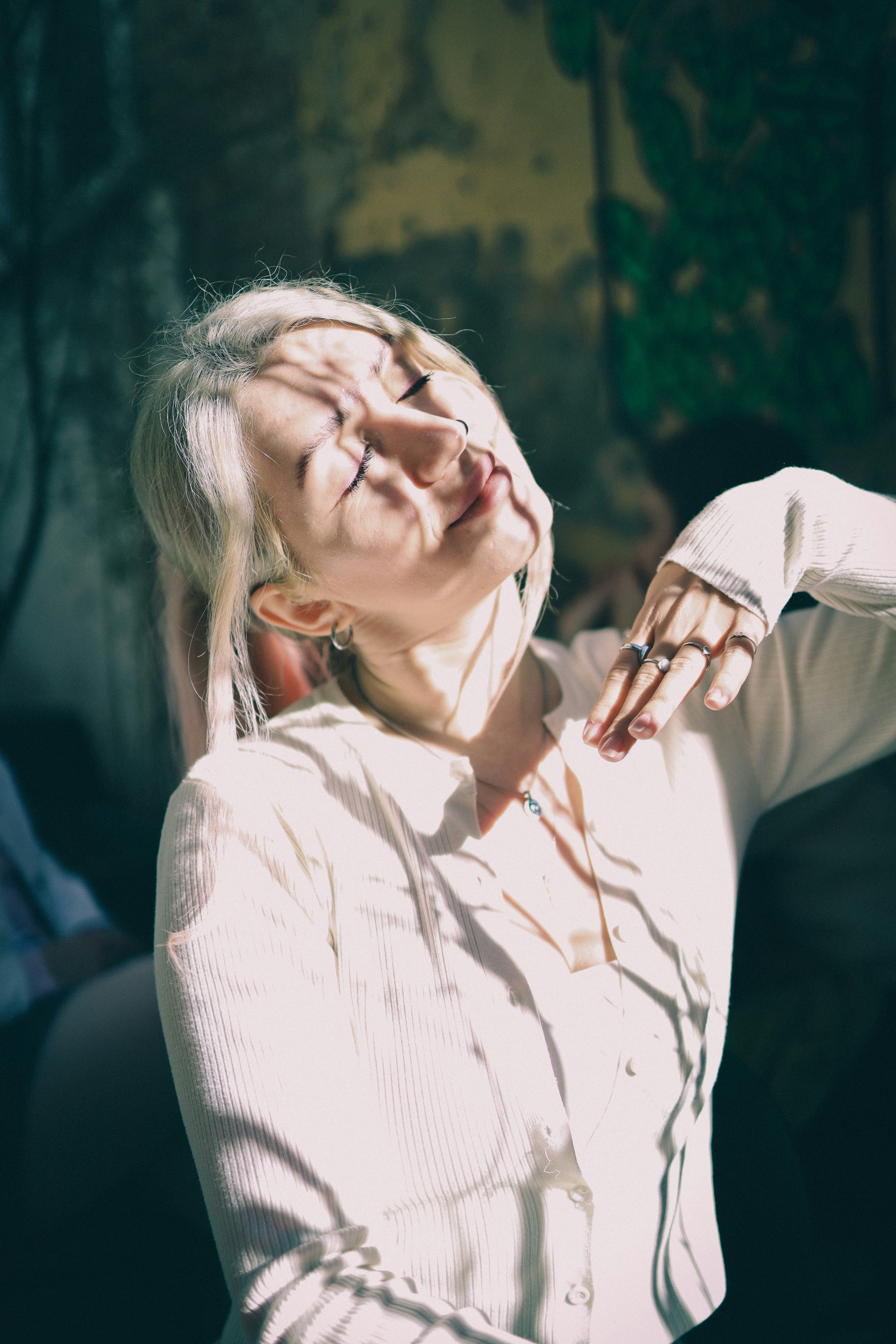 Woman with eyes closed bathed in dappled sunlight