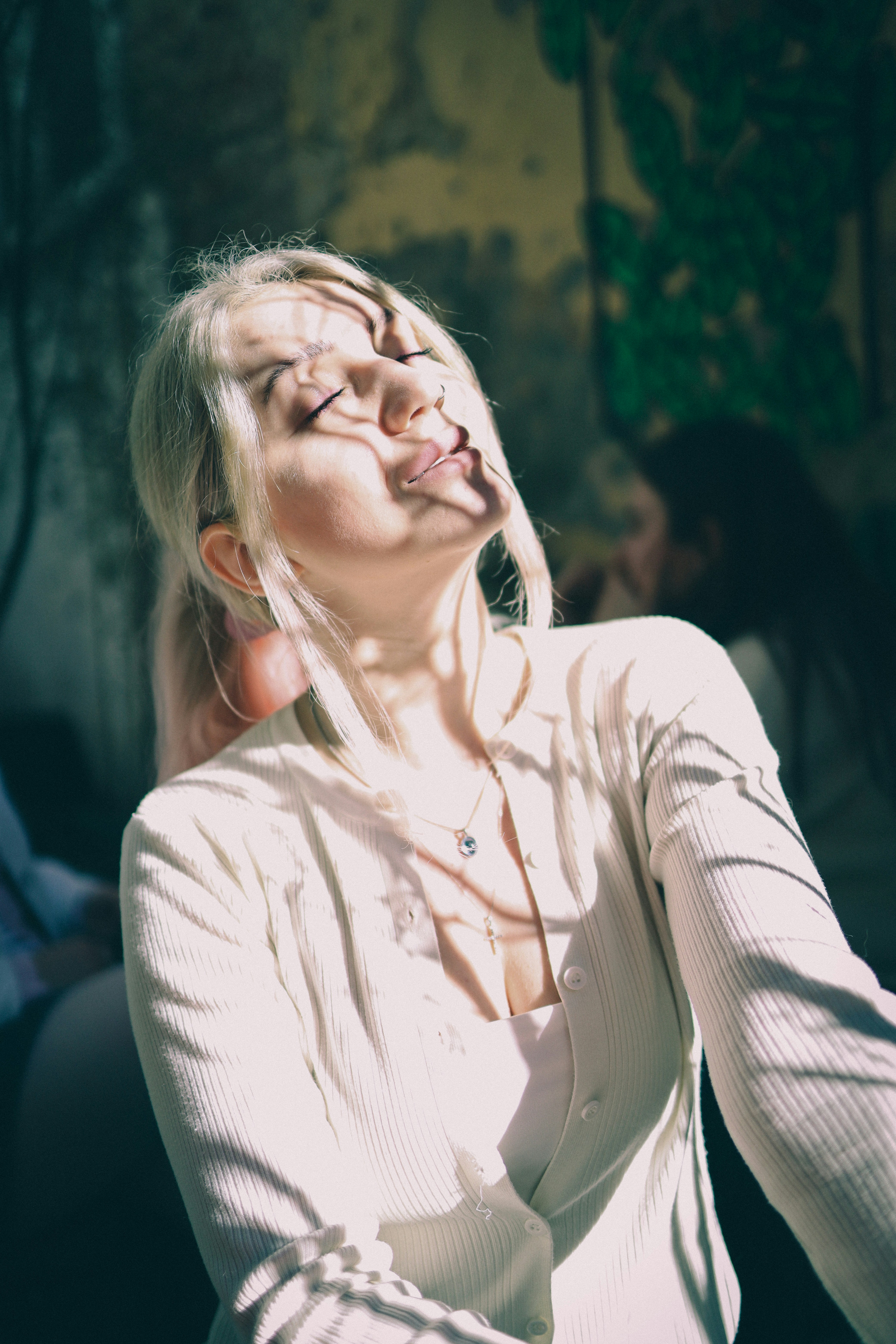 Woman with blond hair bathed in sunlight and shadows.