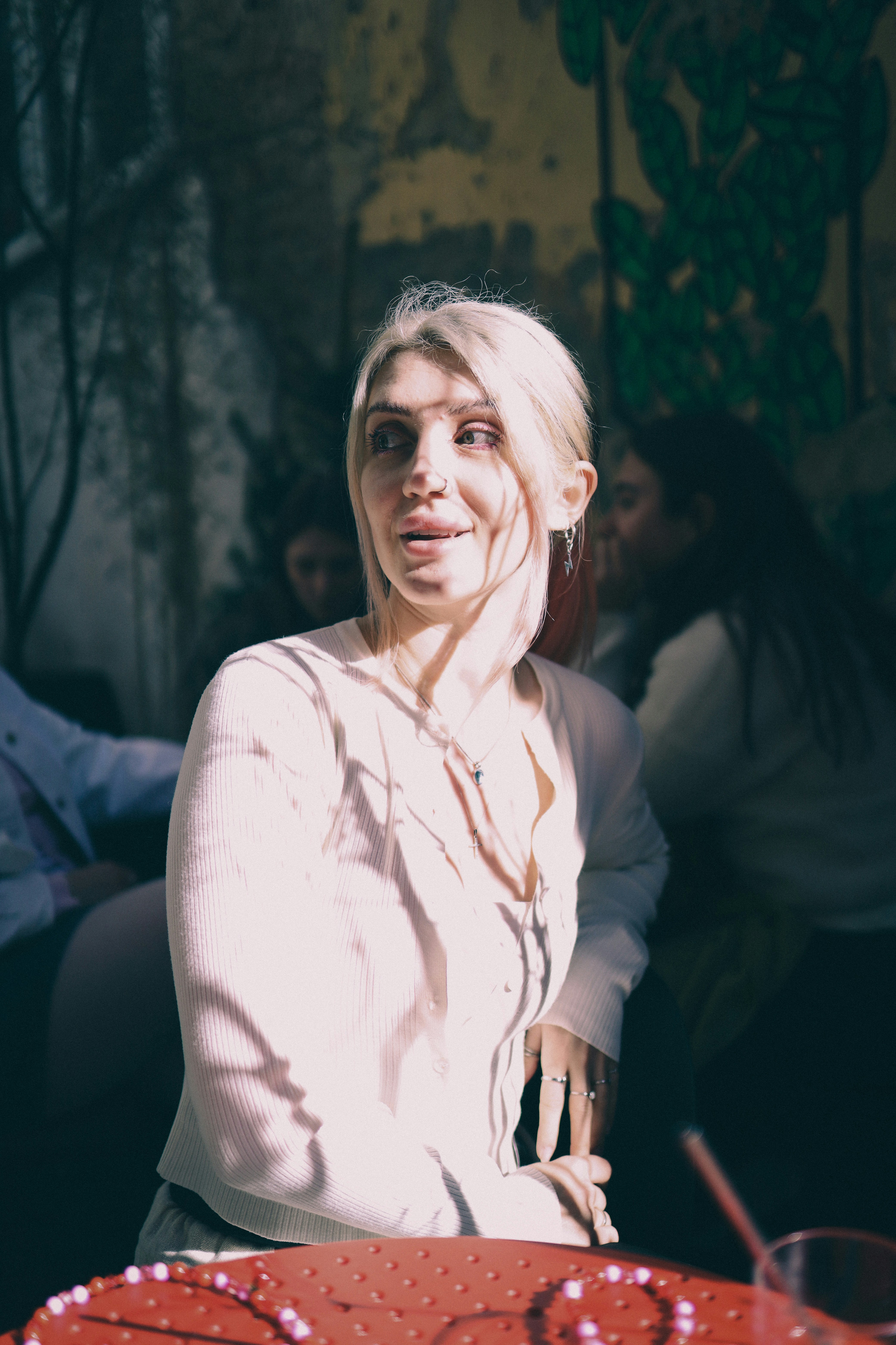 A woman with blonde hair wearing a white cardigan.