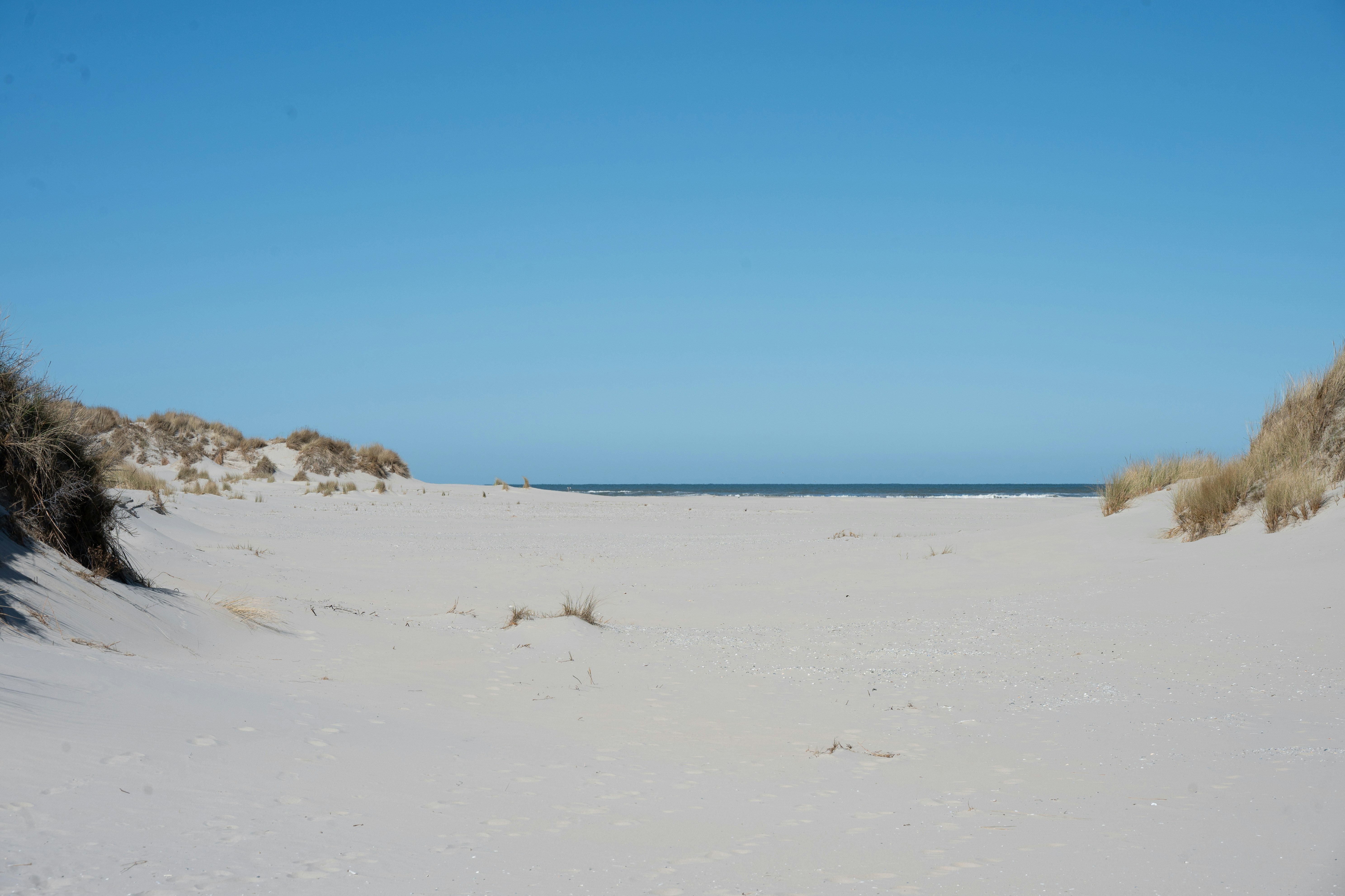 Pantai berpasir dengan bukit pasir dan langit biru cerah