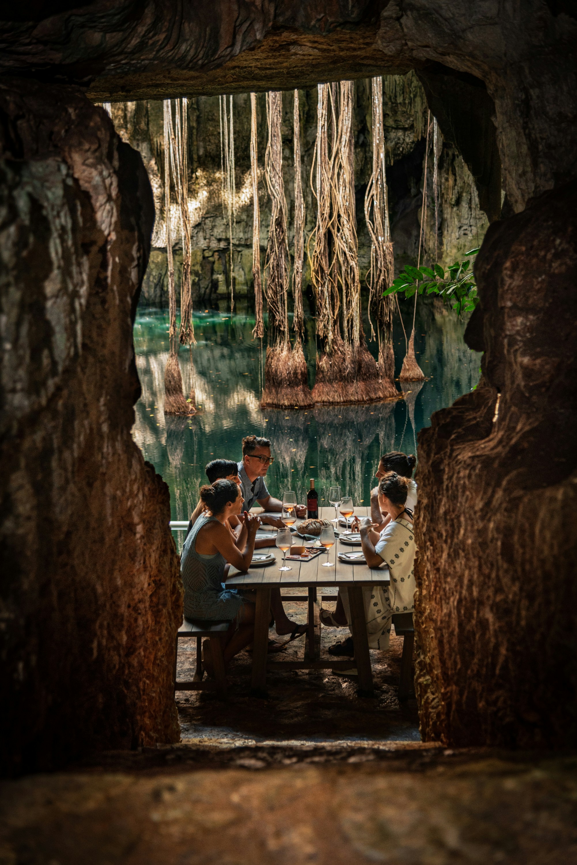 Group enjoying a meal in a cenote with roots overhead