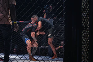 Two fighters grappling inside a cage