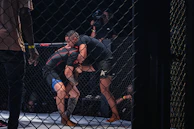 Two fighters grappling inside a cage