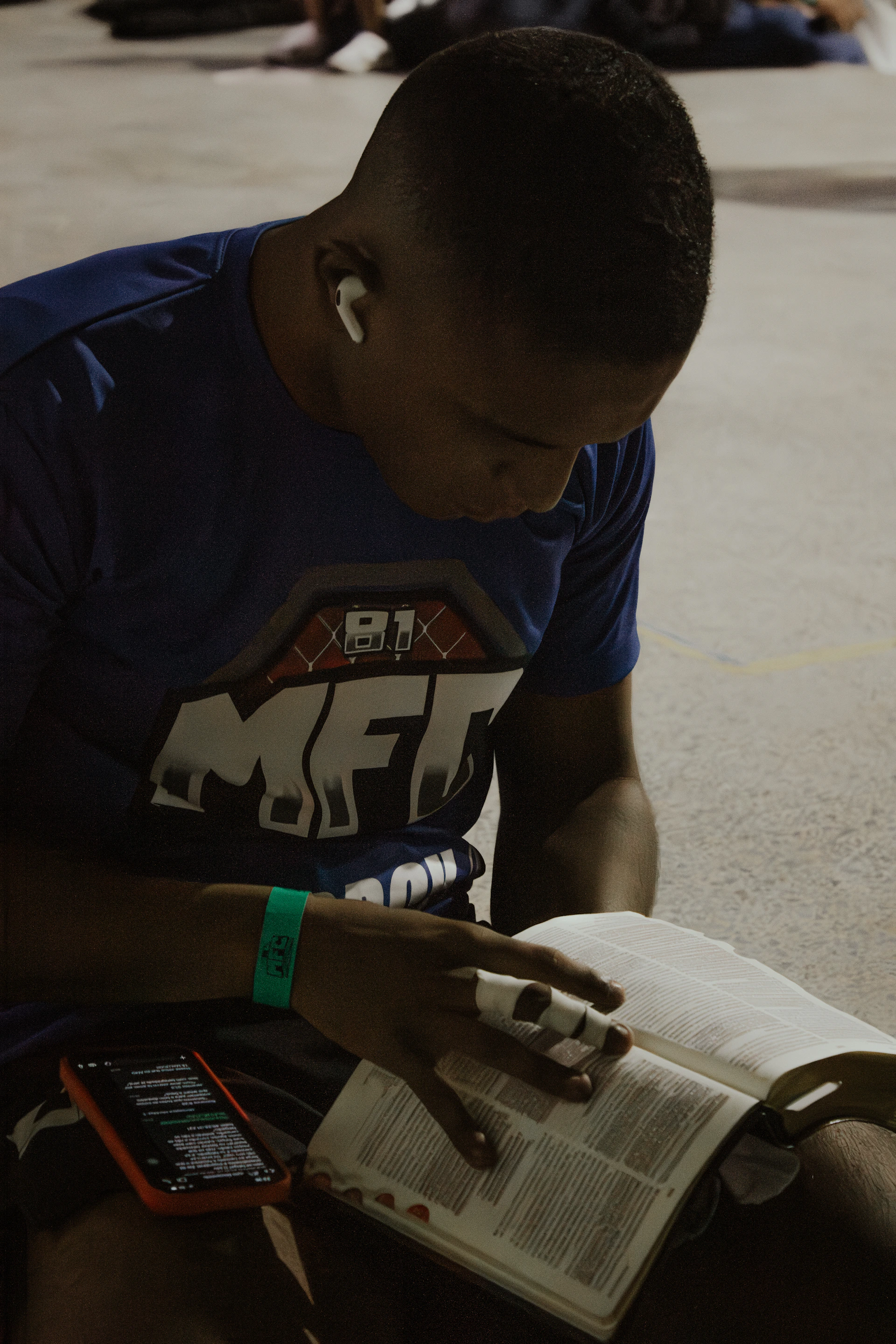 Young man reading a book with earbuds in