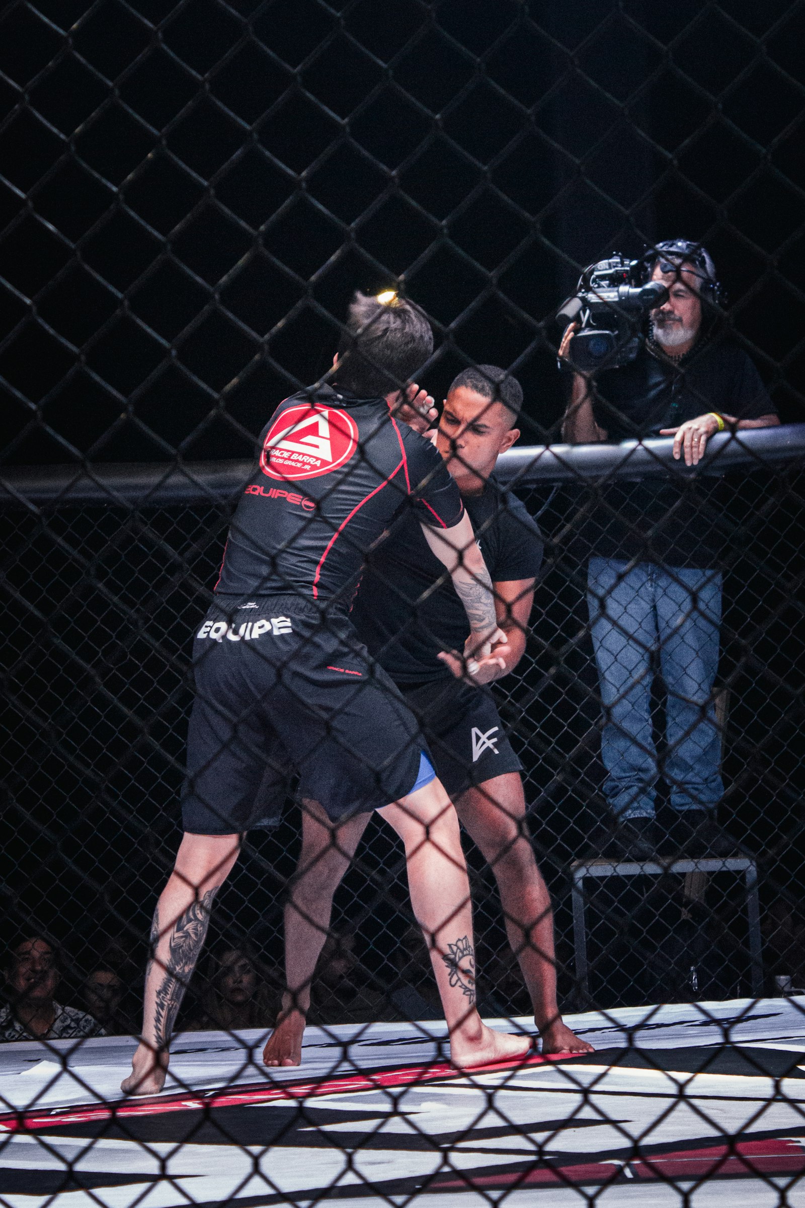 Two MMA fighters grappling inside octagon cage