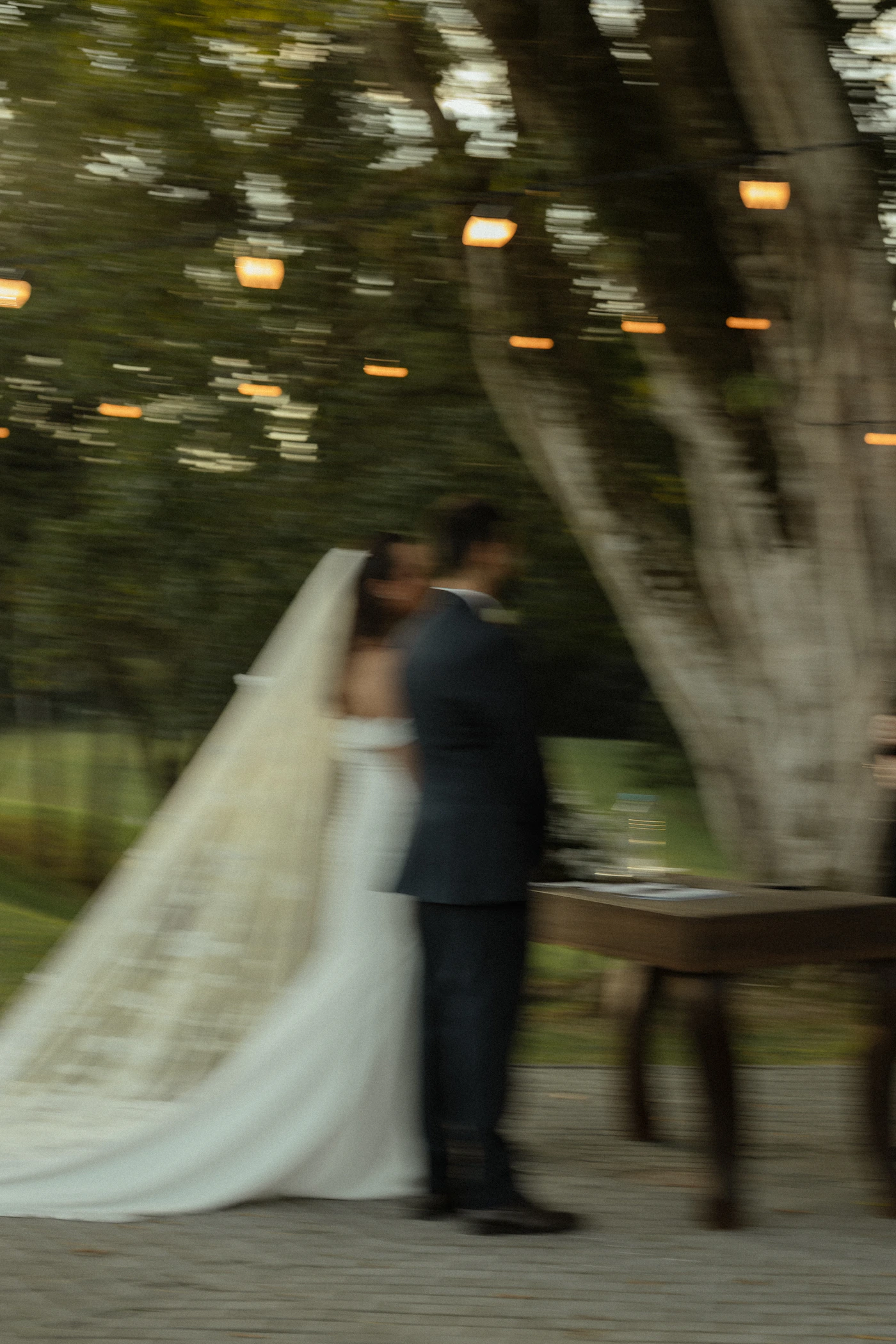 A bride and groom standing together at their outdoor wedding ceremony in elegant formal wedding attire with natural light and the outdoor ceremony setting visible around them